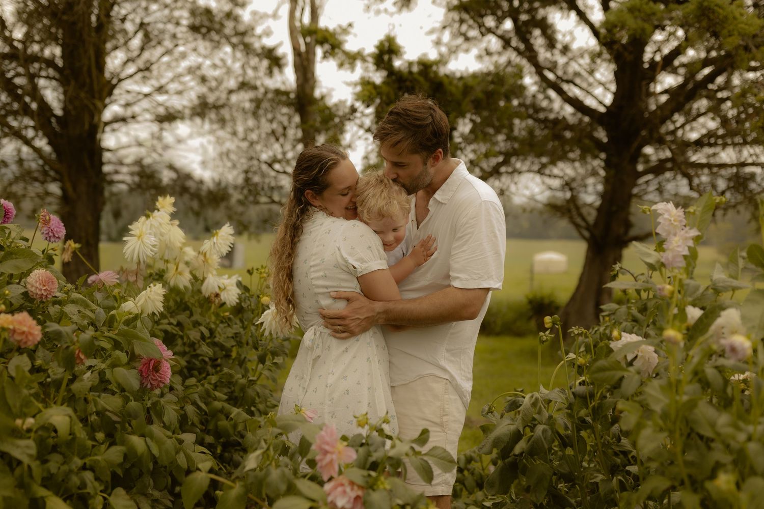 A romantic couple embraces tenderly in a lush garden setting during a golden hour photoshoot.