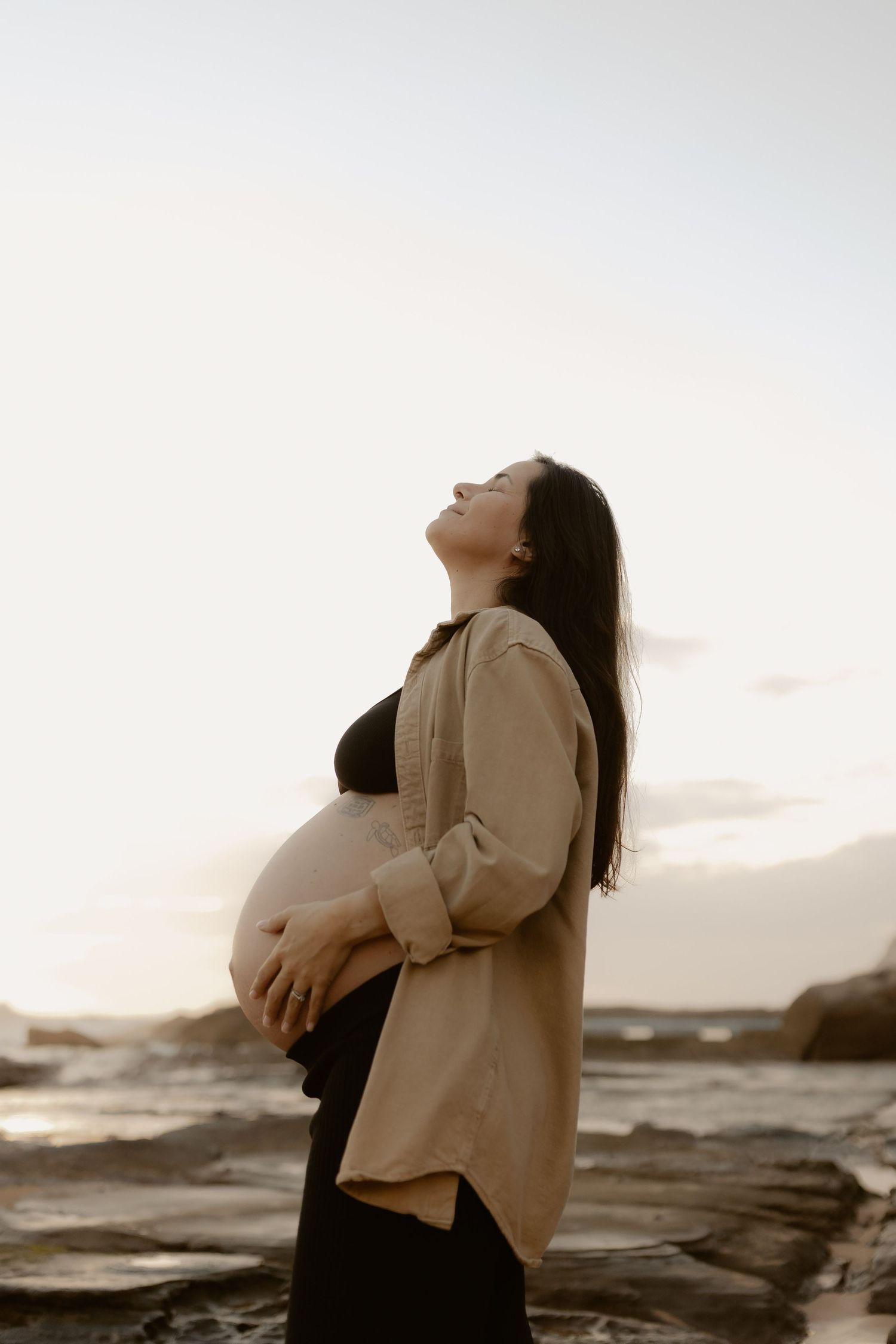 A couple shares intimate moments against a dramatic coastal backdrop during sunset.