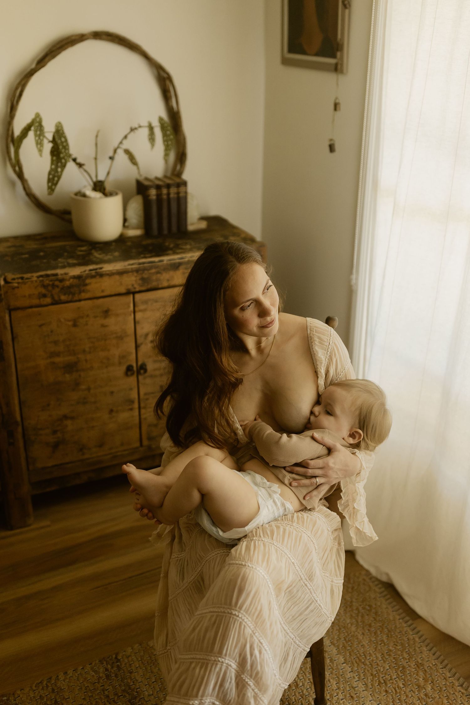 A soft sepia-toned photo series shows tender maternal moments in a minimalist interior with wooden furniture.