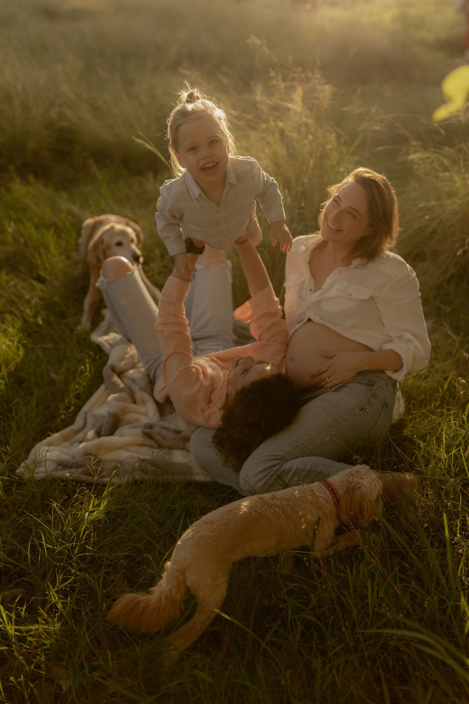 Candid family moments captured during sunset in a grassy field.