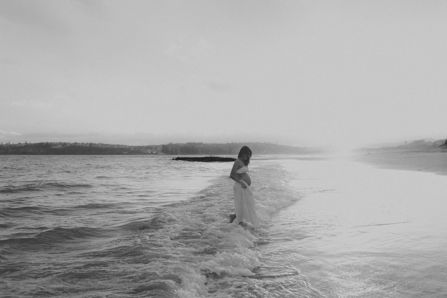 Silhouette of a surfer riding waves on a misty ocean horizon.