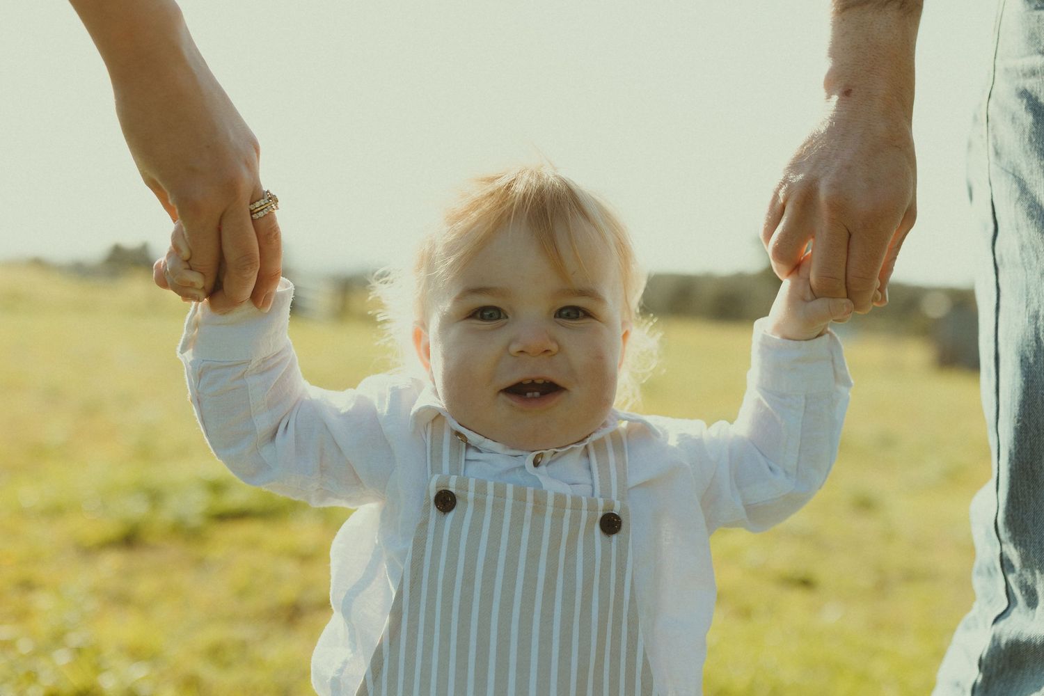 Collage of happy toddler wearing white clothing playing outdoors in golden sunlit field at sunset.