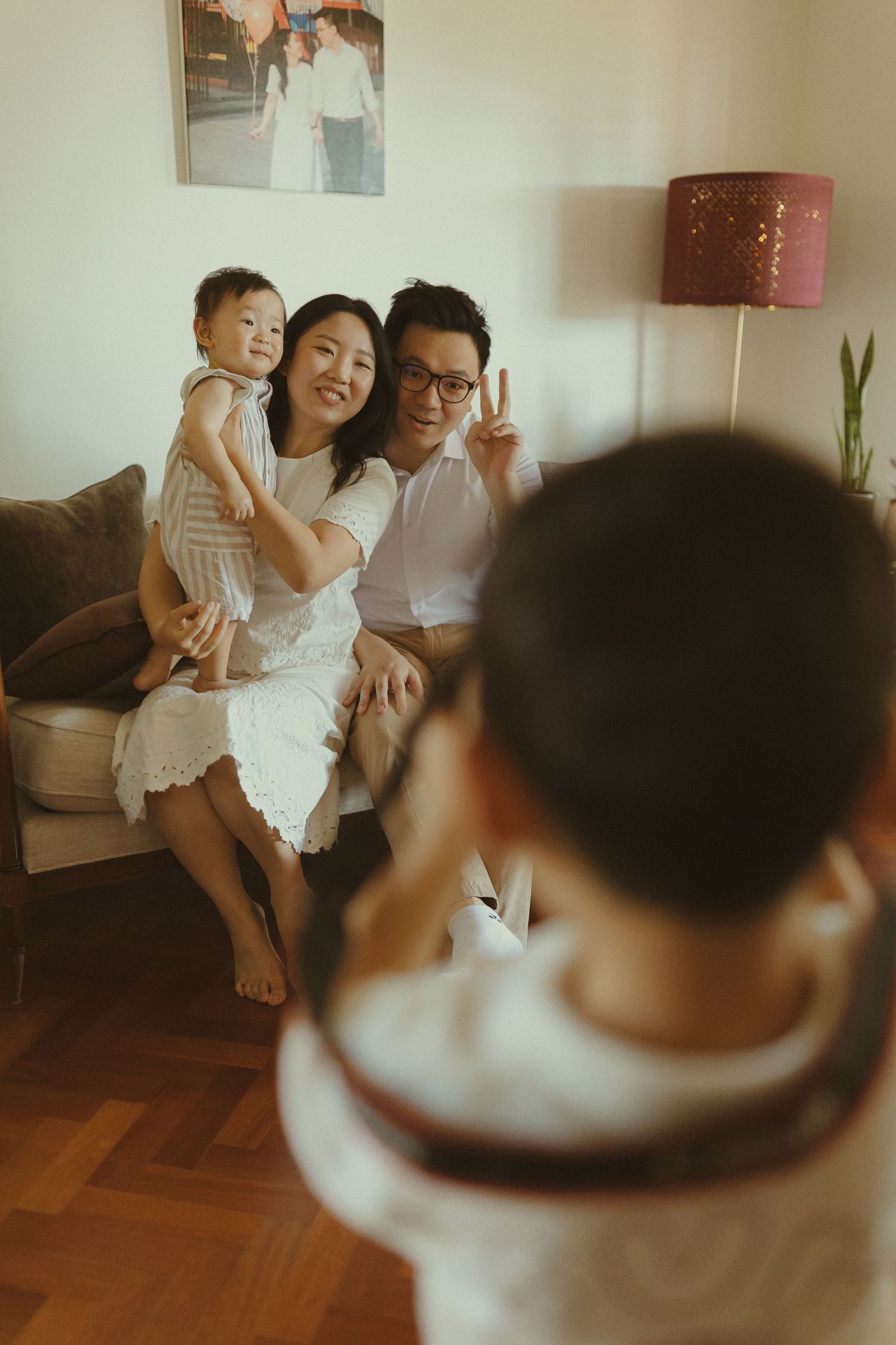Candid family moments captured on a cozy sofa in a living room with warm lighting.