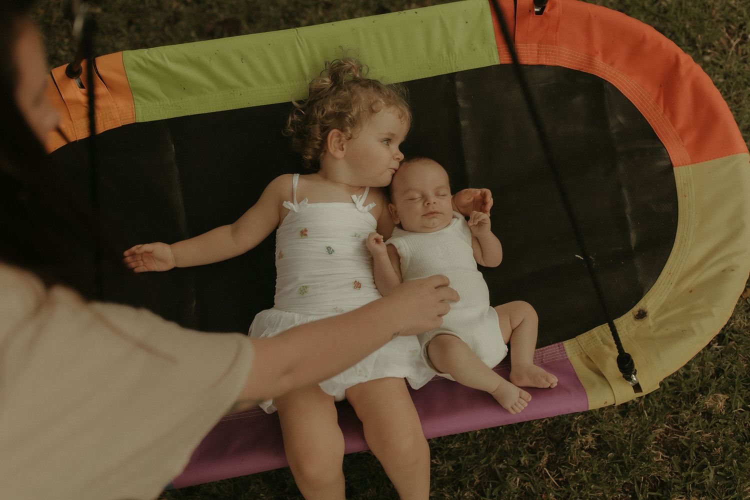 A playful moment on a colorful blanket with a baby in white clothing.
