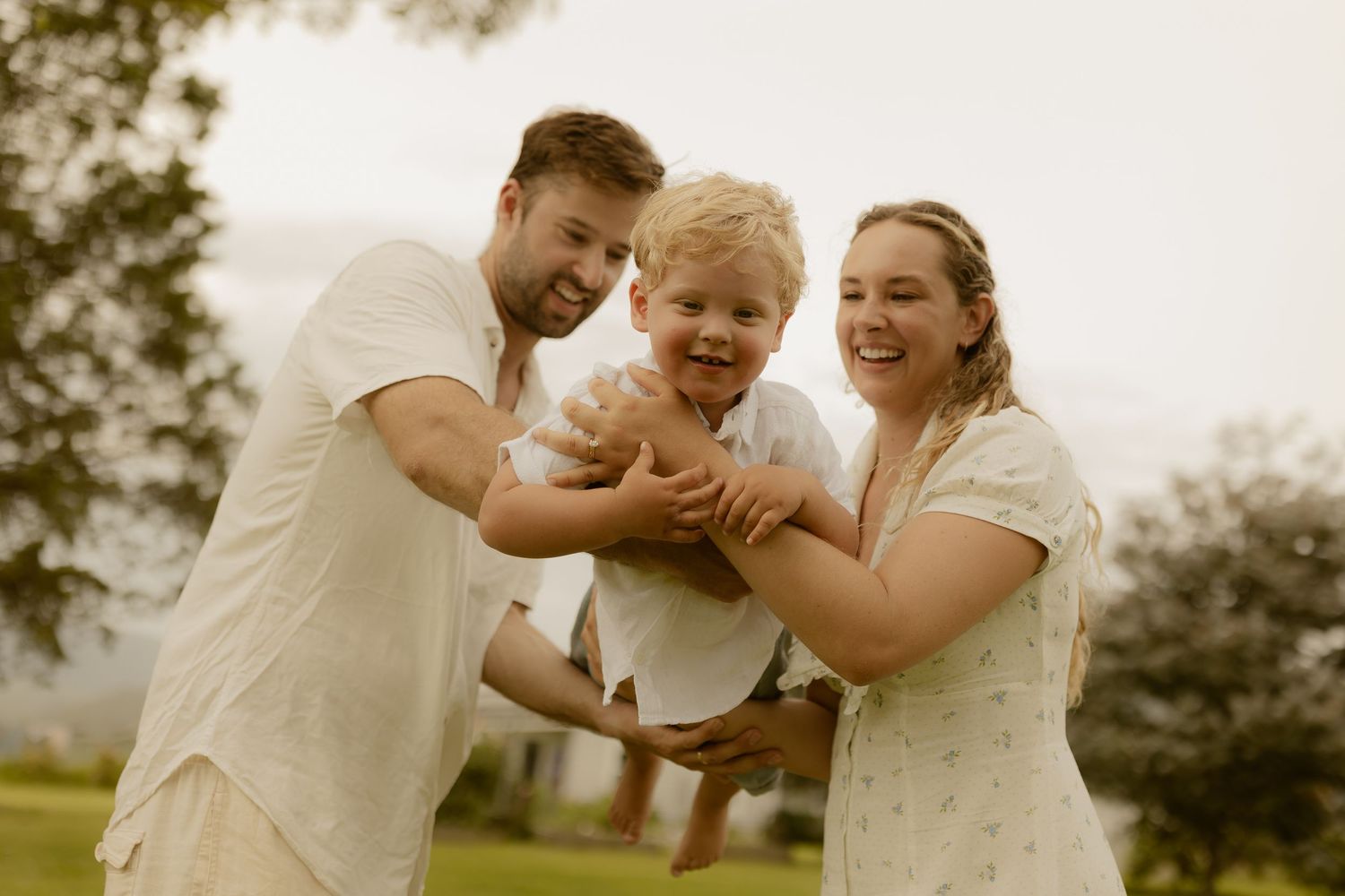 A joyful outdoor family moment captured in warm sunlight against a rural backdrop.