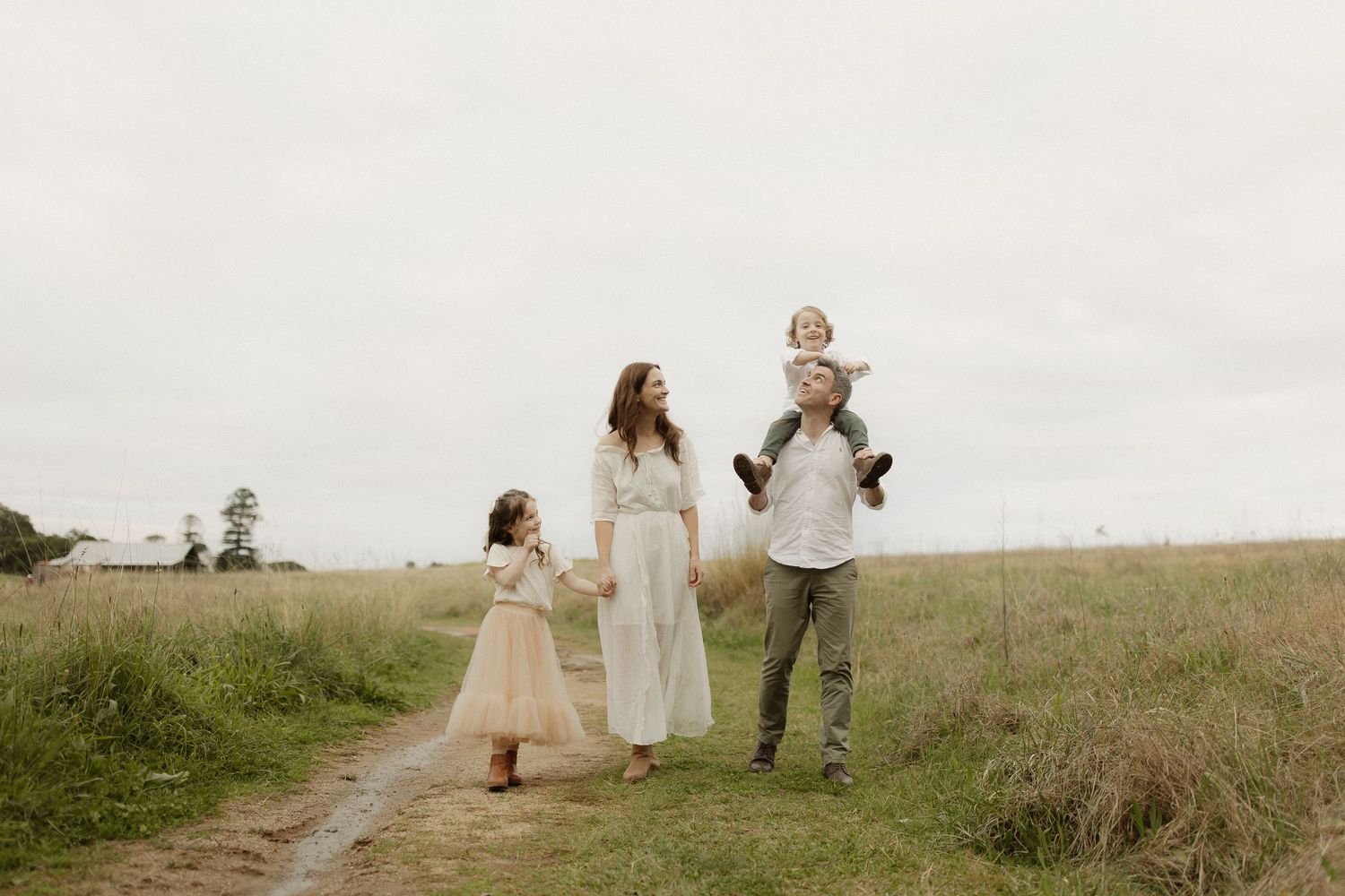 Family walks hand in hand along a scenic rural path during golden hour.