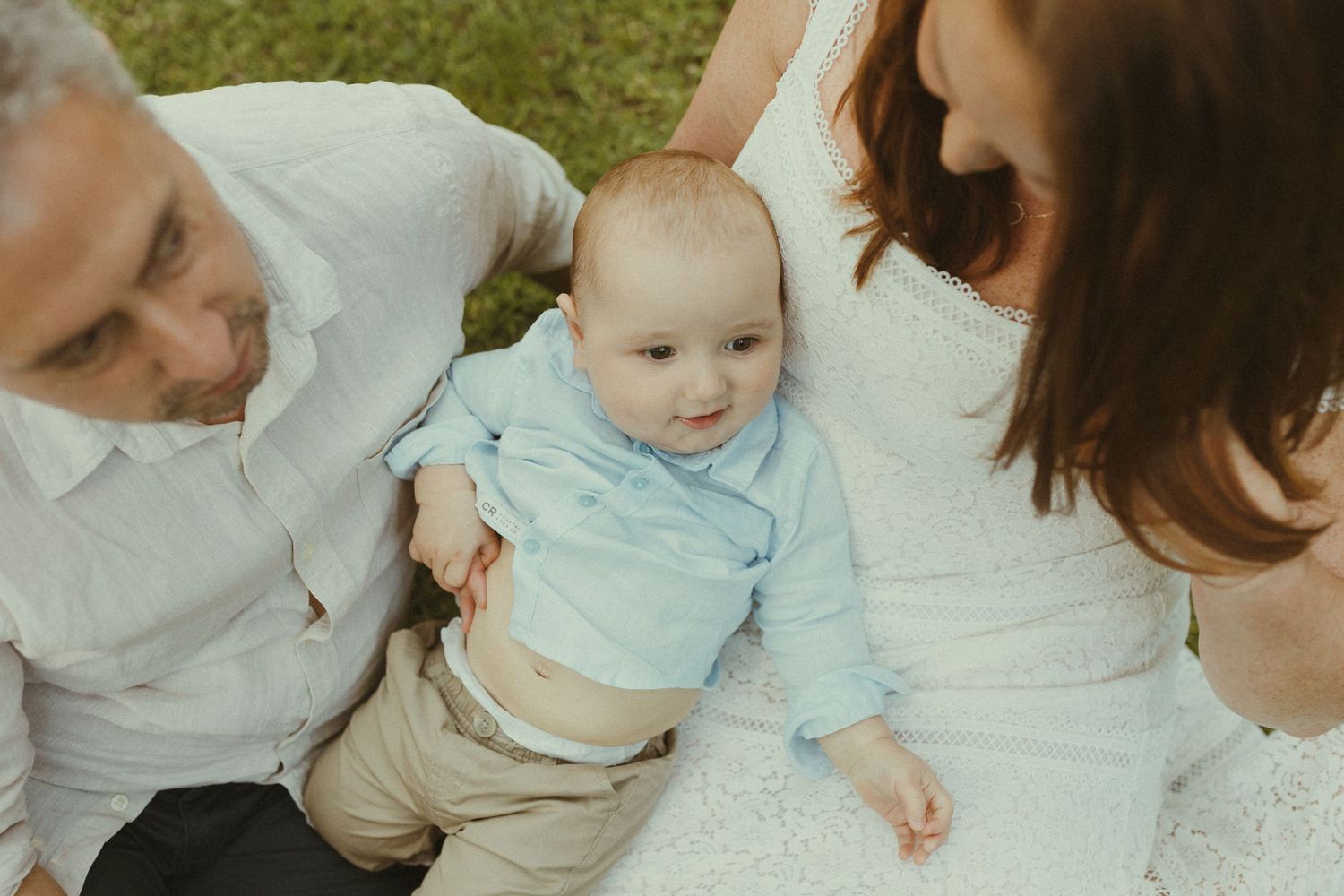 A tender family moment captured in soft natural light while sitting together on a white surface.