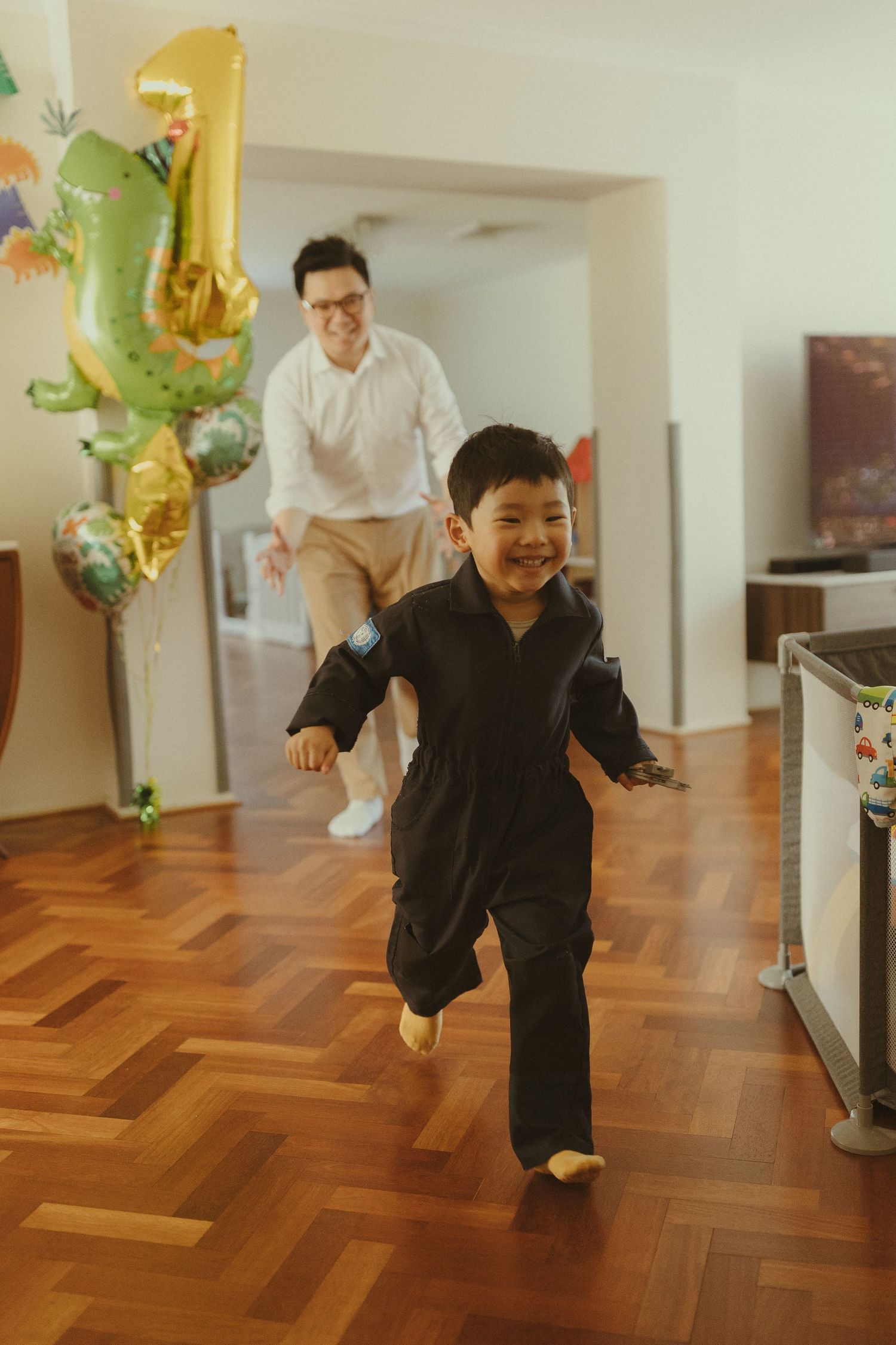 Playful sequence showing a person in black running and jumping across a hardwood floor with decorative balloons.