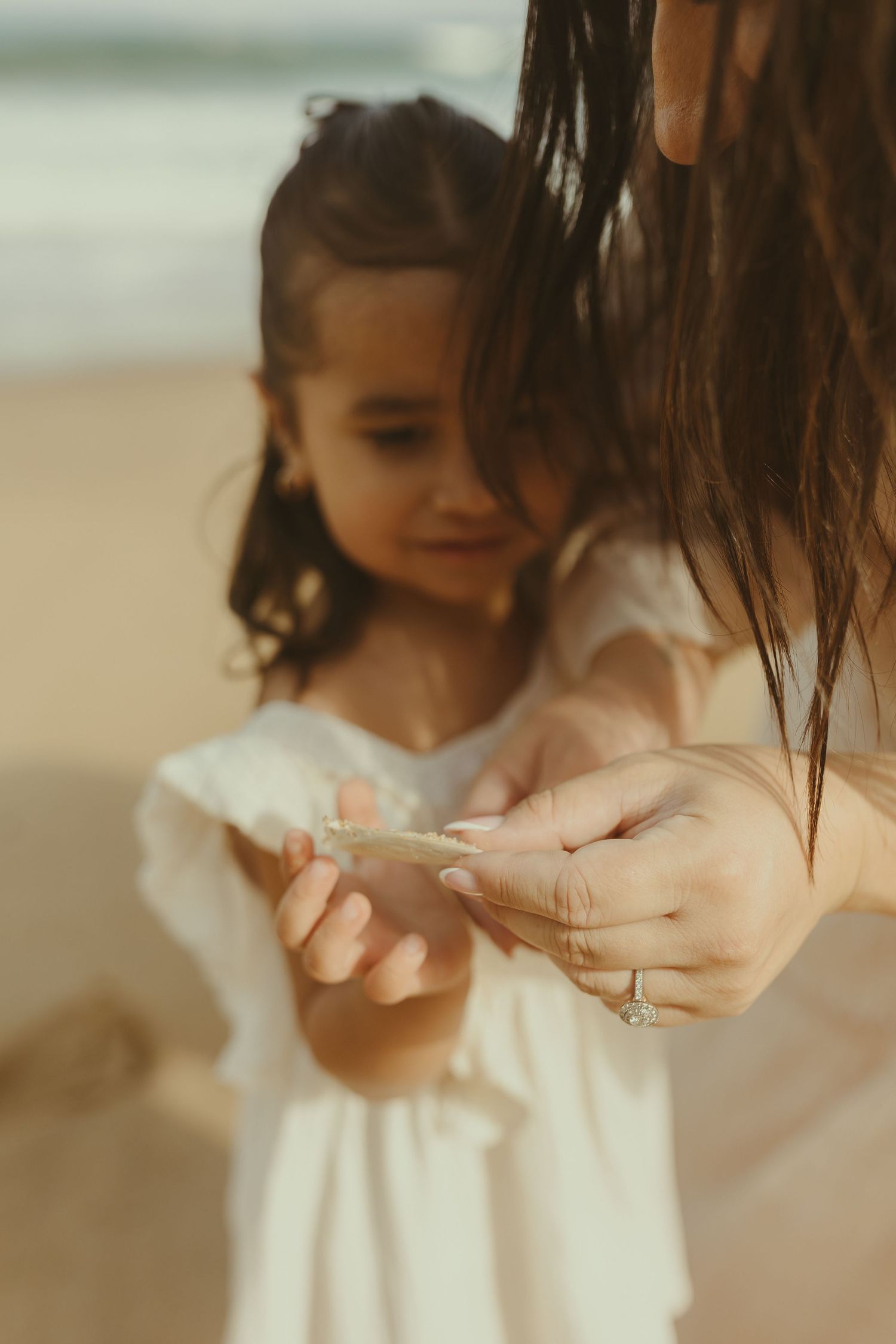 A young child in a white dress holds out their hands gently in a series of connected artistic photographs.