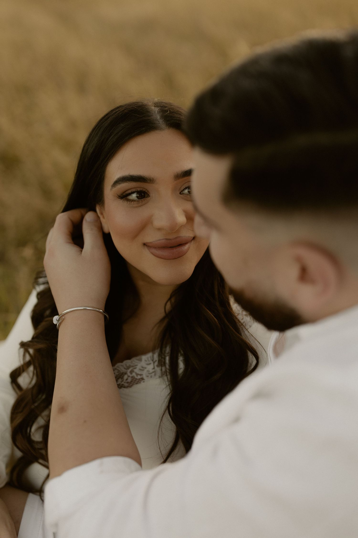 A romantic close-up moment between a couple with soft golden lighting and natural expressions.