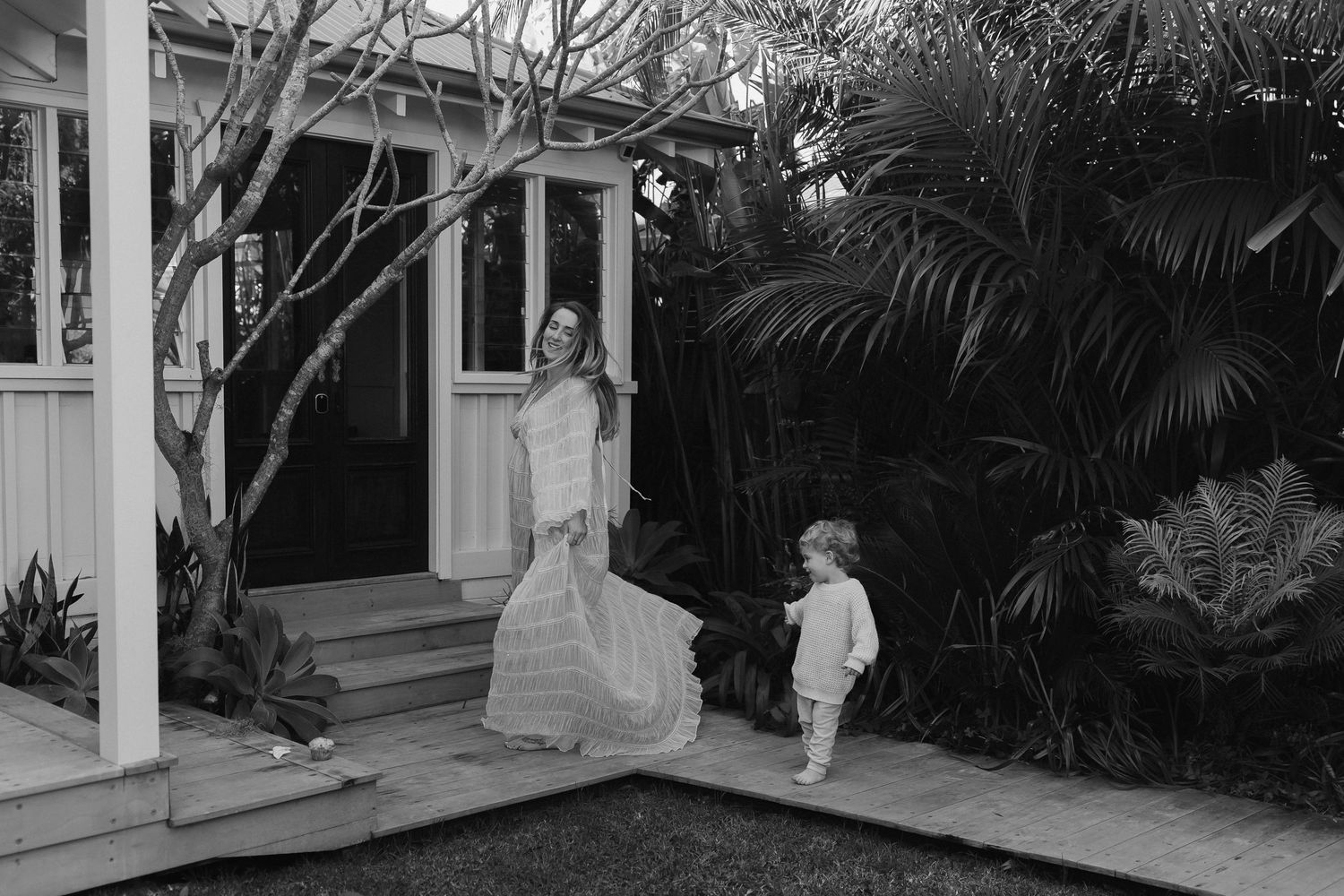 Black and white photo of a charming domestic scene on a porch with tropical plants.