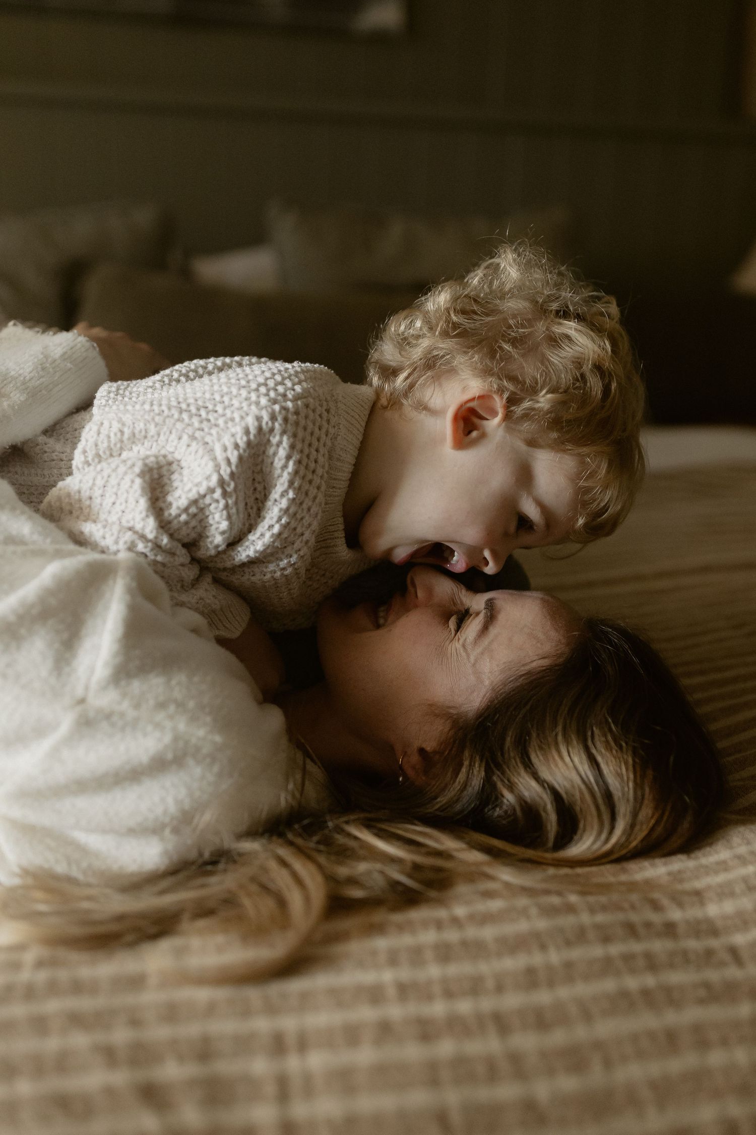 A tender moment of connection and affection on a cozy bed with neutral tones and soft lighting.