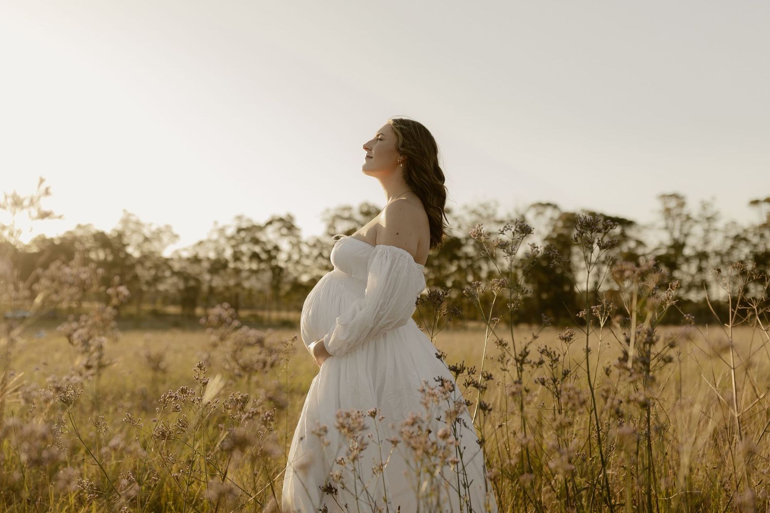 White-dressed figures standing in a sunlit meadow during golden hour.