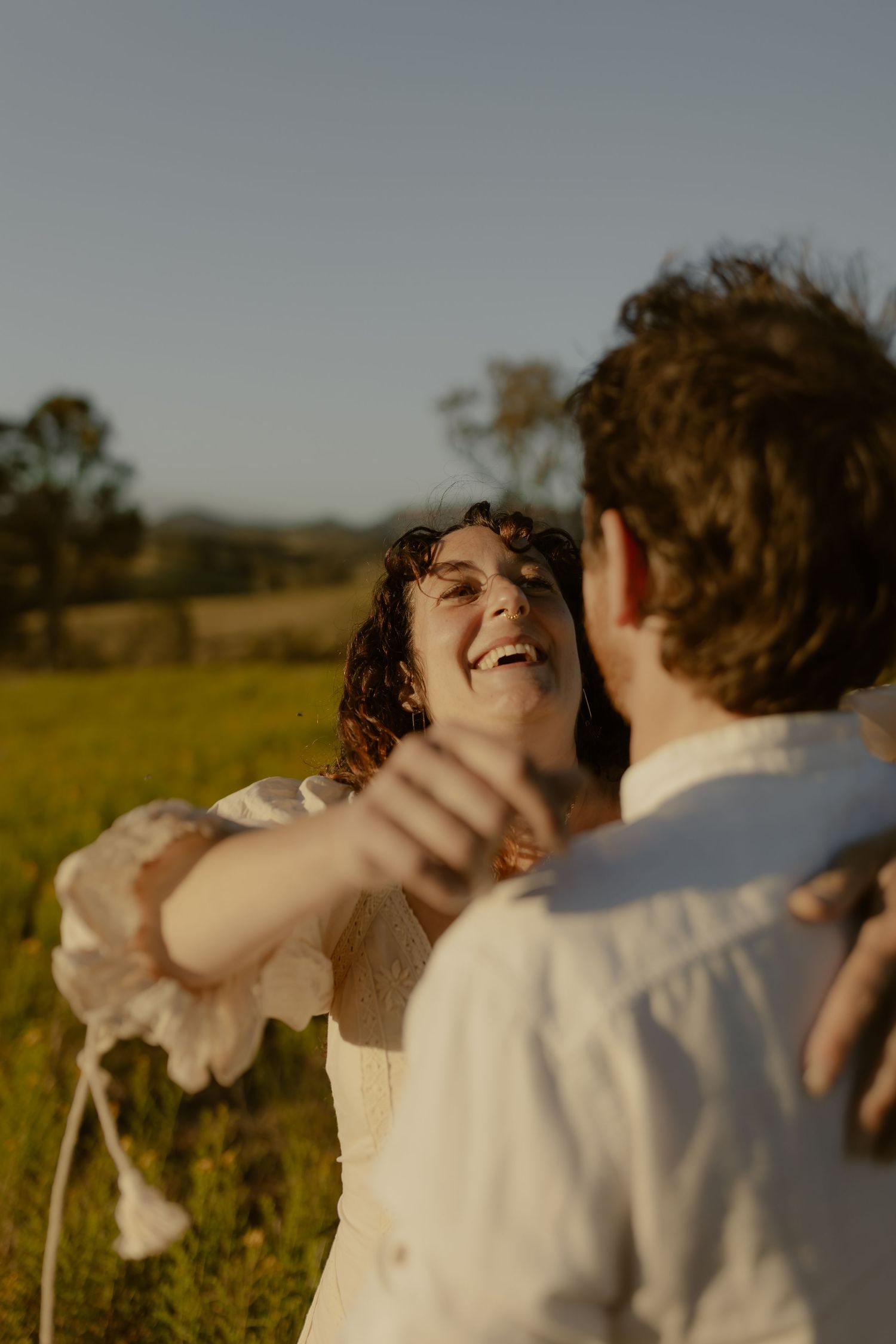 A joyful moment captured in a sun-drenched field with natural movement and laughter.