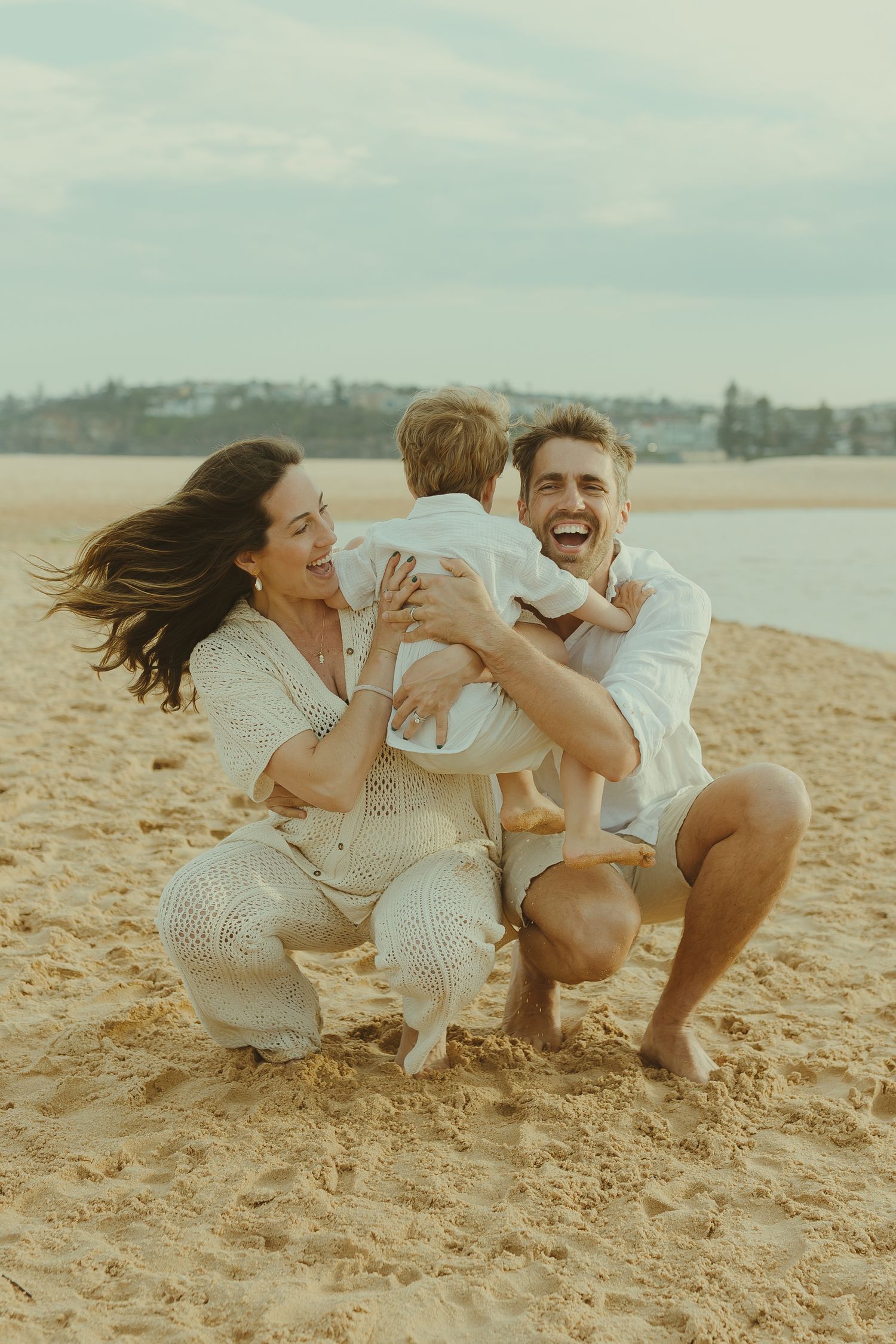 Playful family moment captured on beach with everyone laughing and having fun.