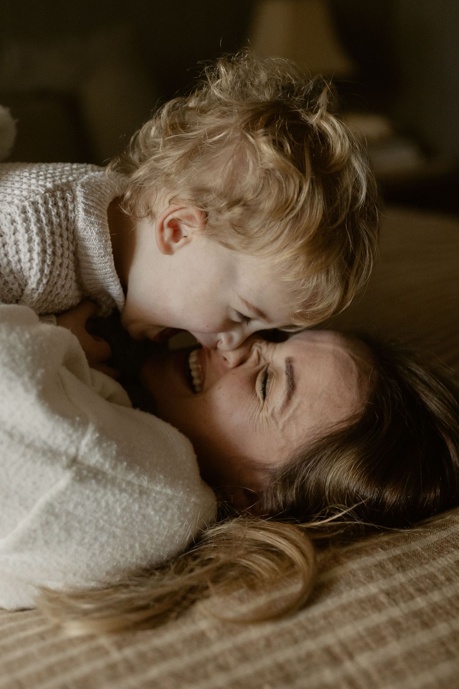 Tender close-up moment of affection and connection on a warm neutral bed.
