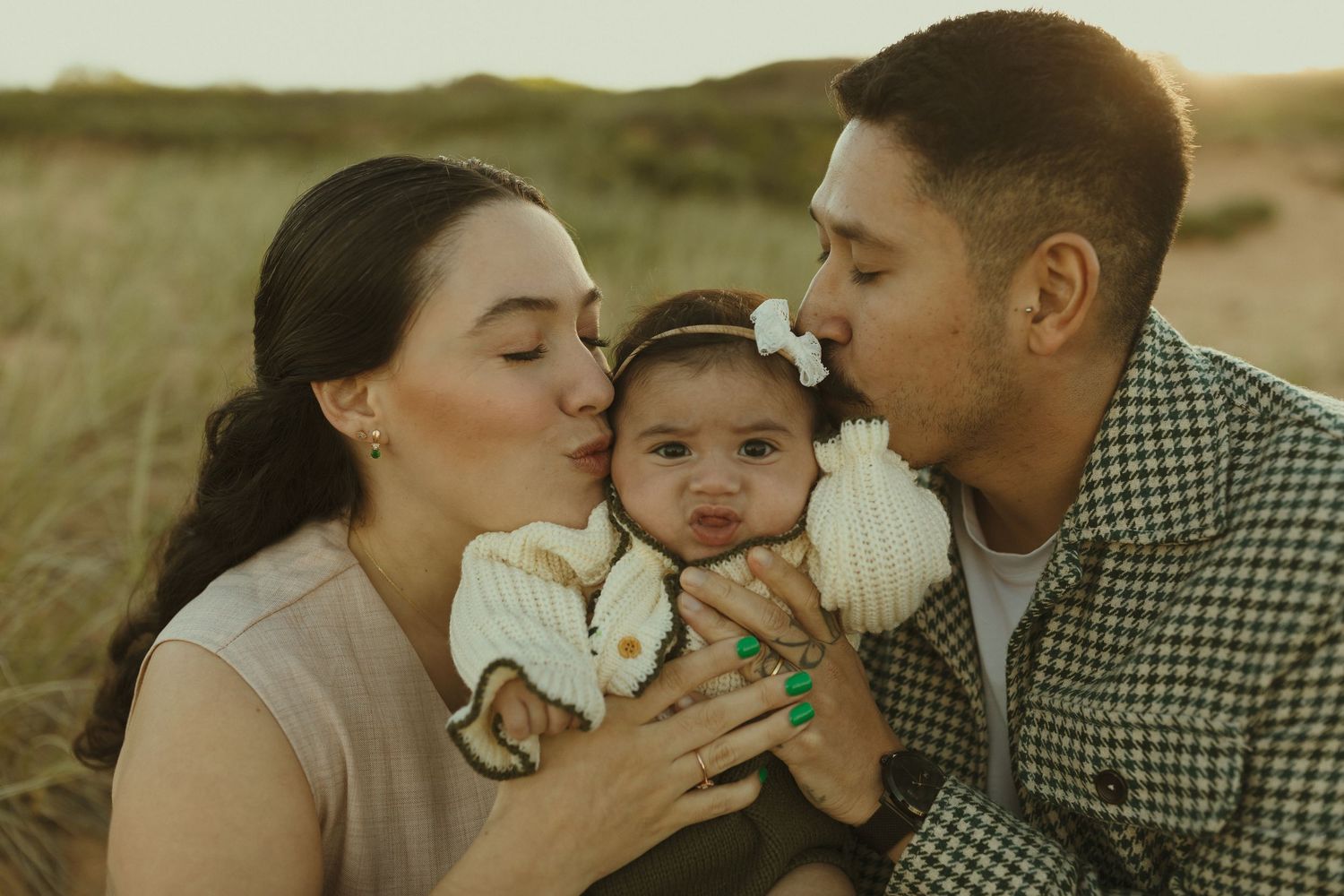 A family shares a tender moment together outdoors in a field during golden hour.