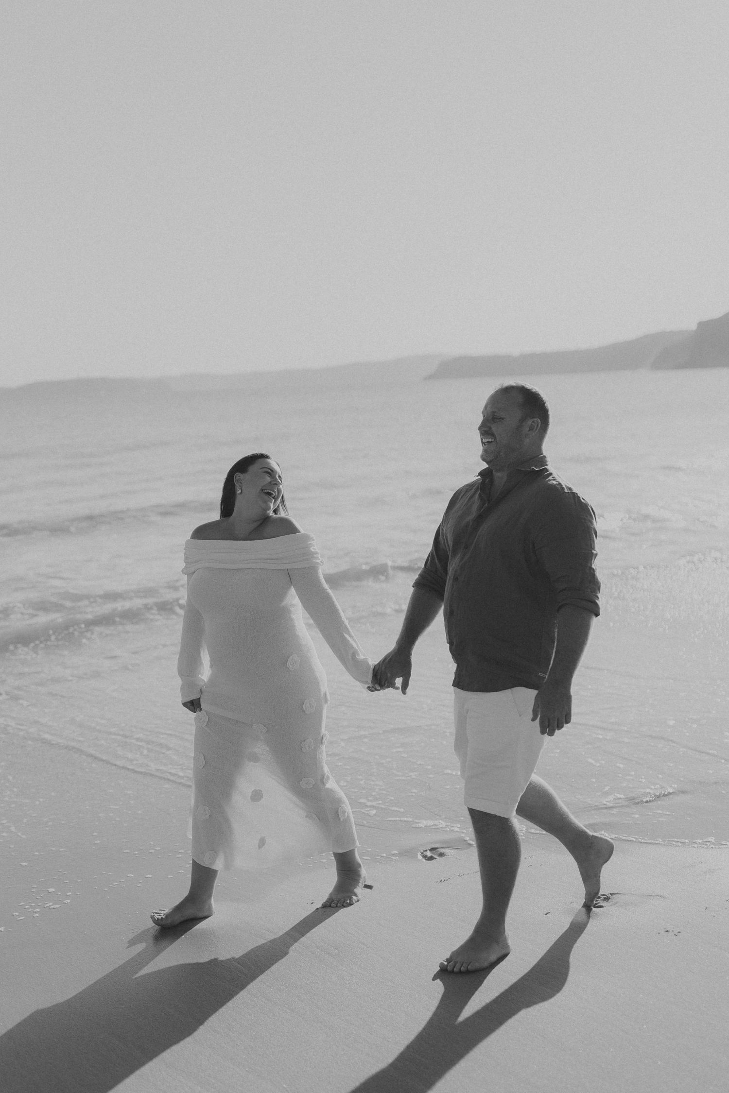 Black and white photo of people running and playing together on a beach.