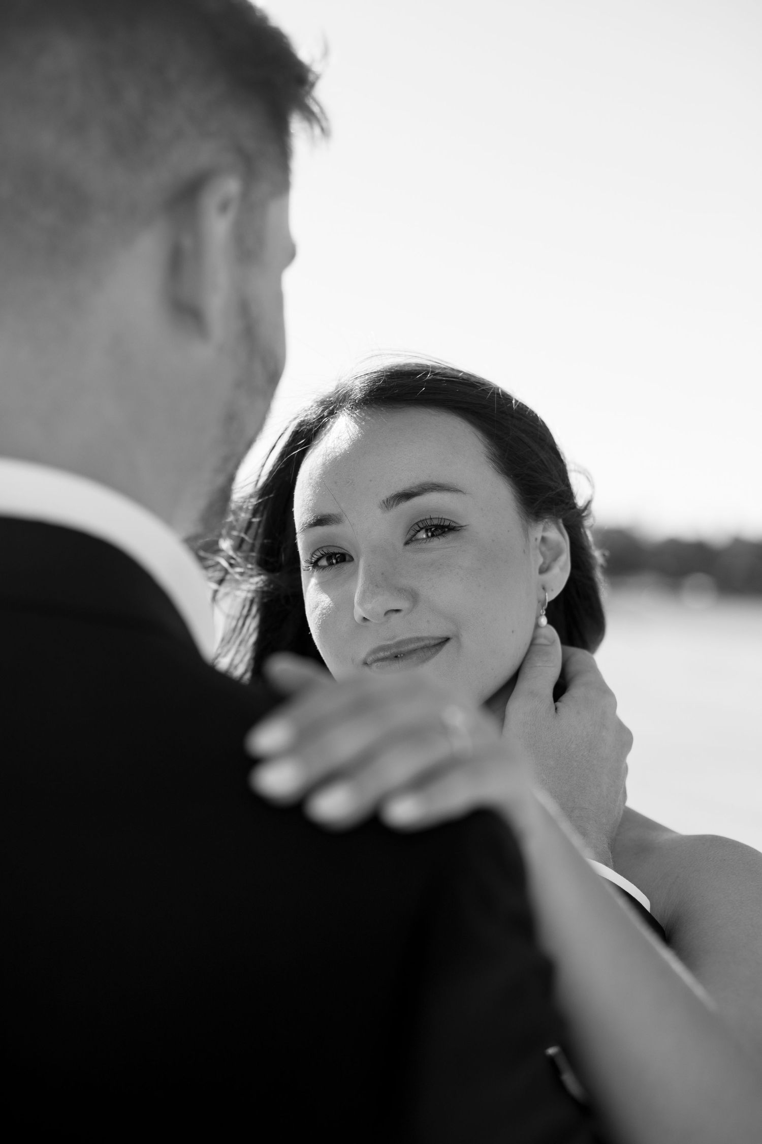 Romantic black and white wedding portrait of couple embracing in soft natural light.