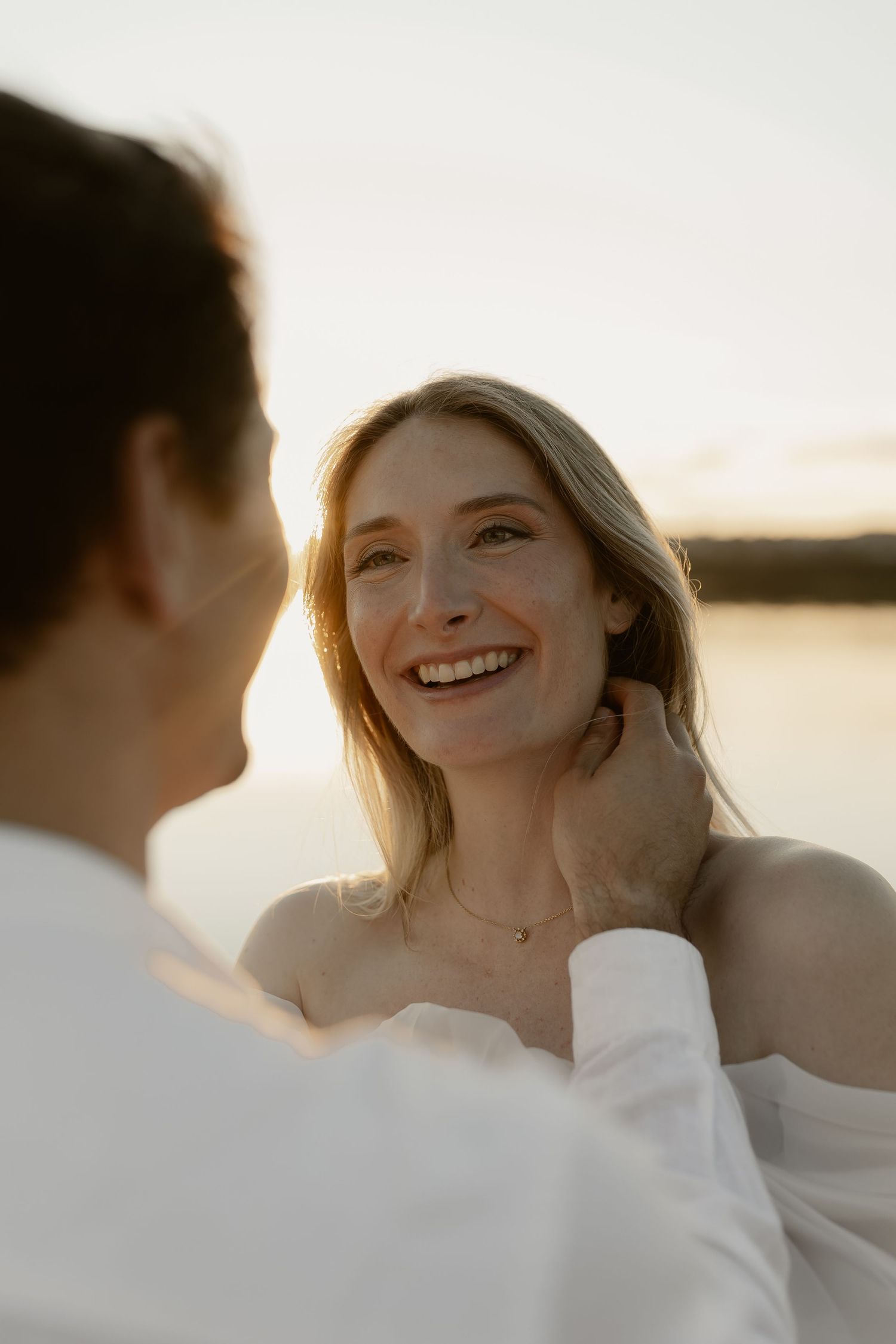 A joyful couple shares intimate moments during their sunset photoshoot by the water.