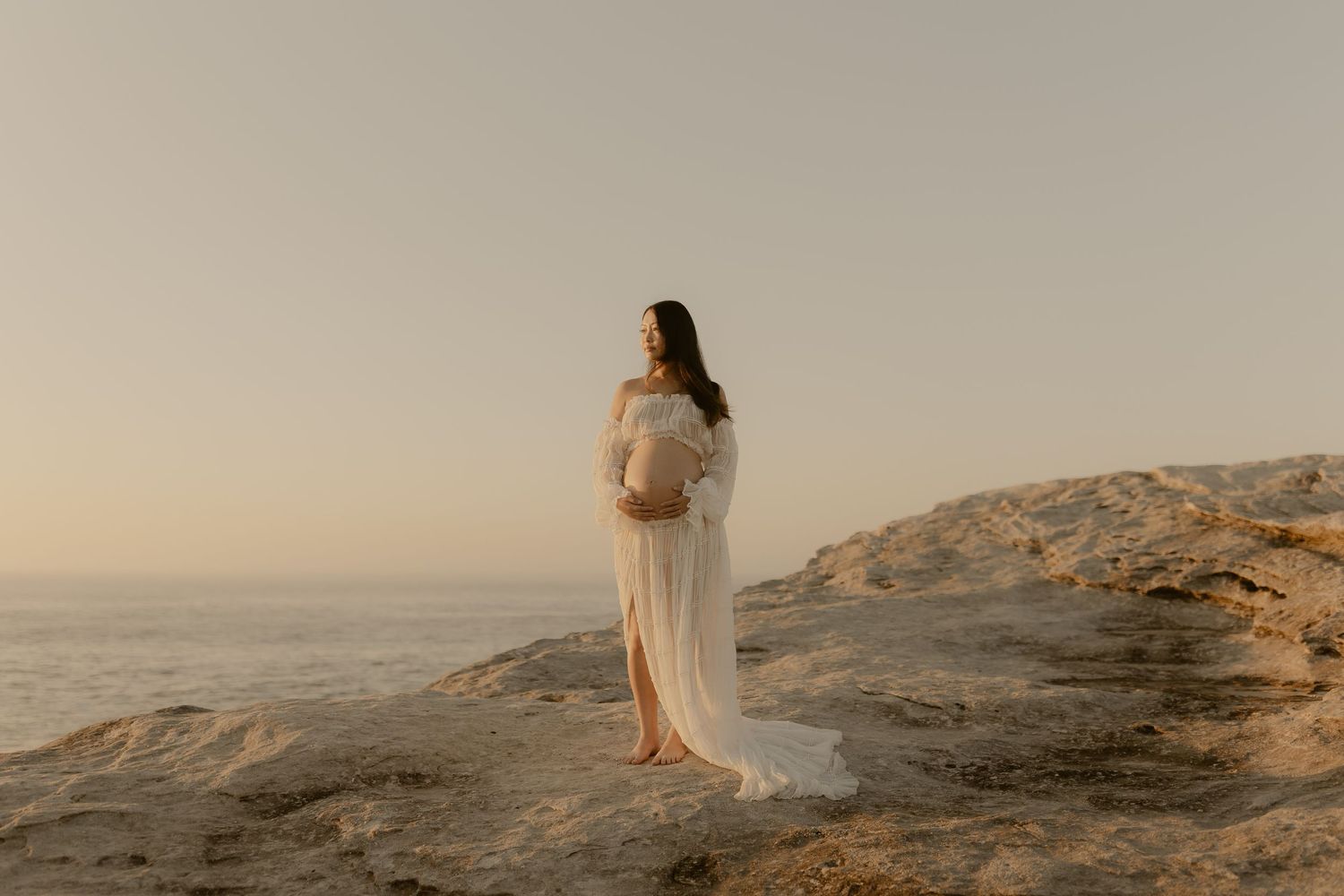 Romantic silhouettes against ocean backdrop during sunset on rocky shoreline.