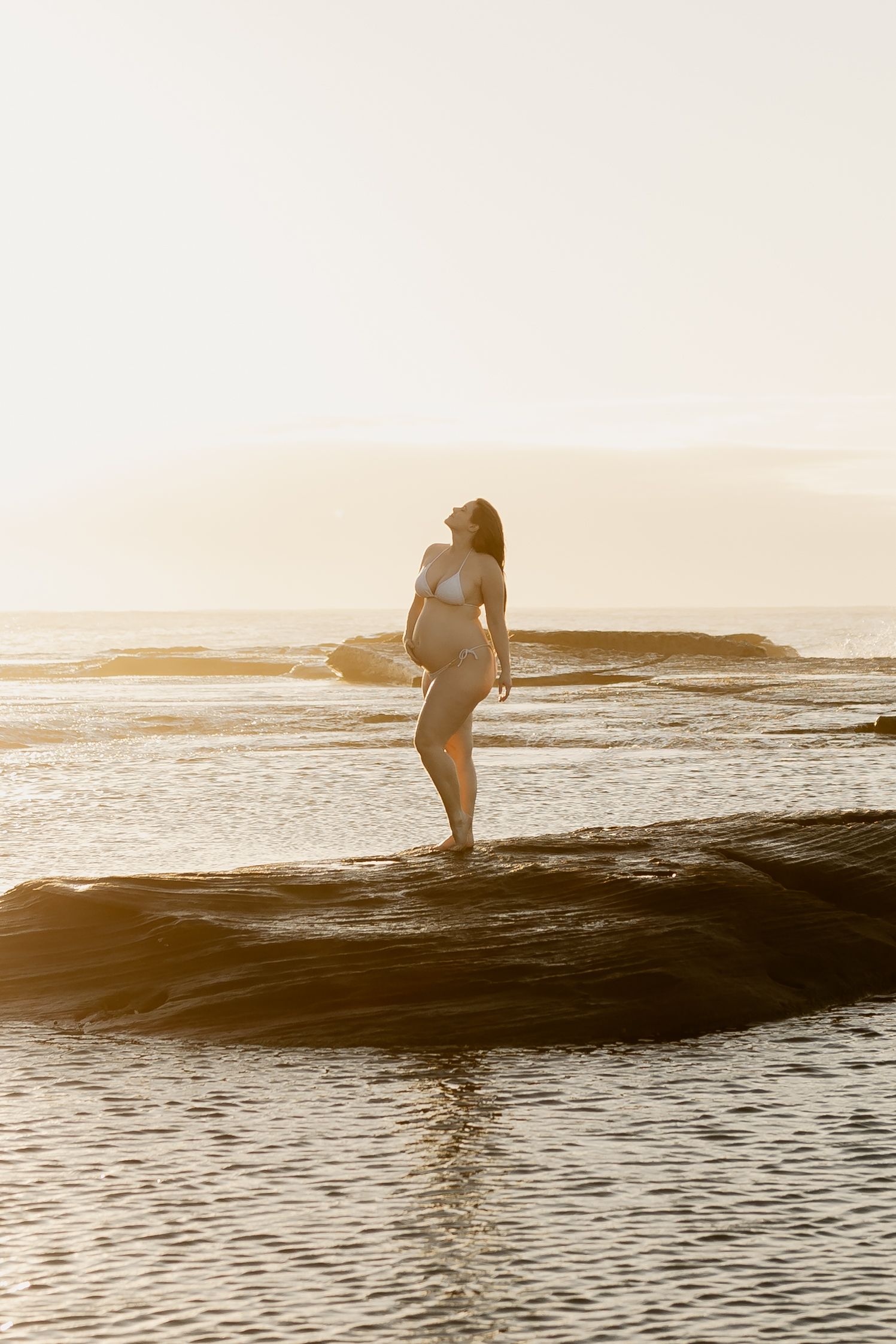 Silhouetted surfer gracefully rides a wave during golden sunset at the ocean.