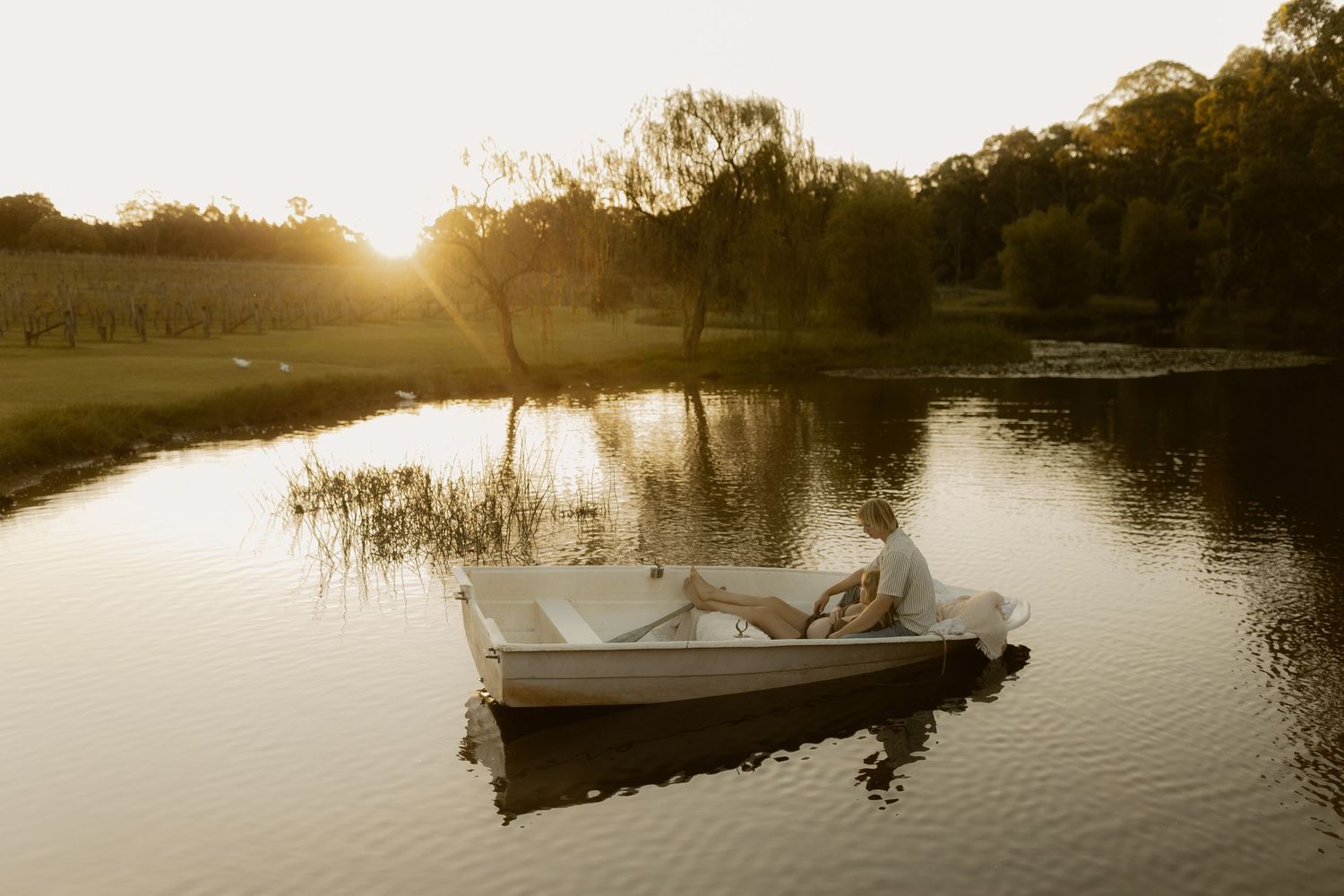 Peaceful lake landscape at sunset with boats and docks silhouetted against golden sky.