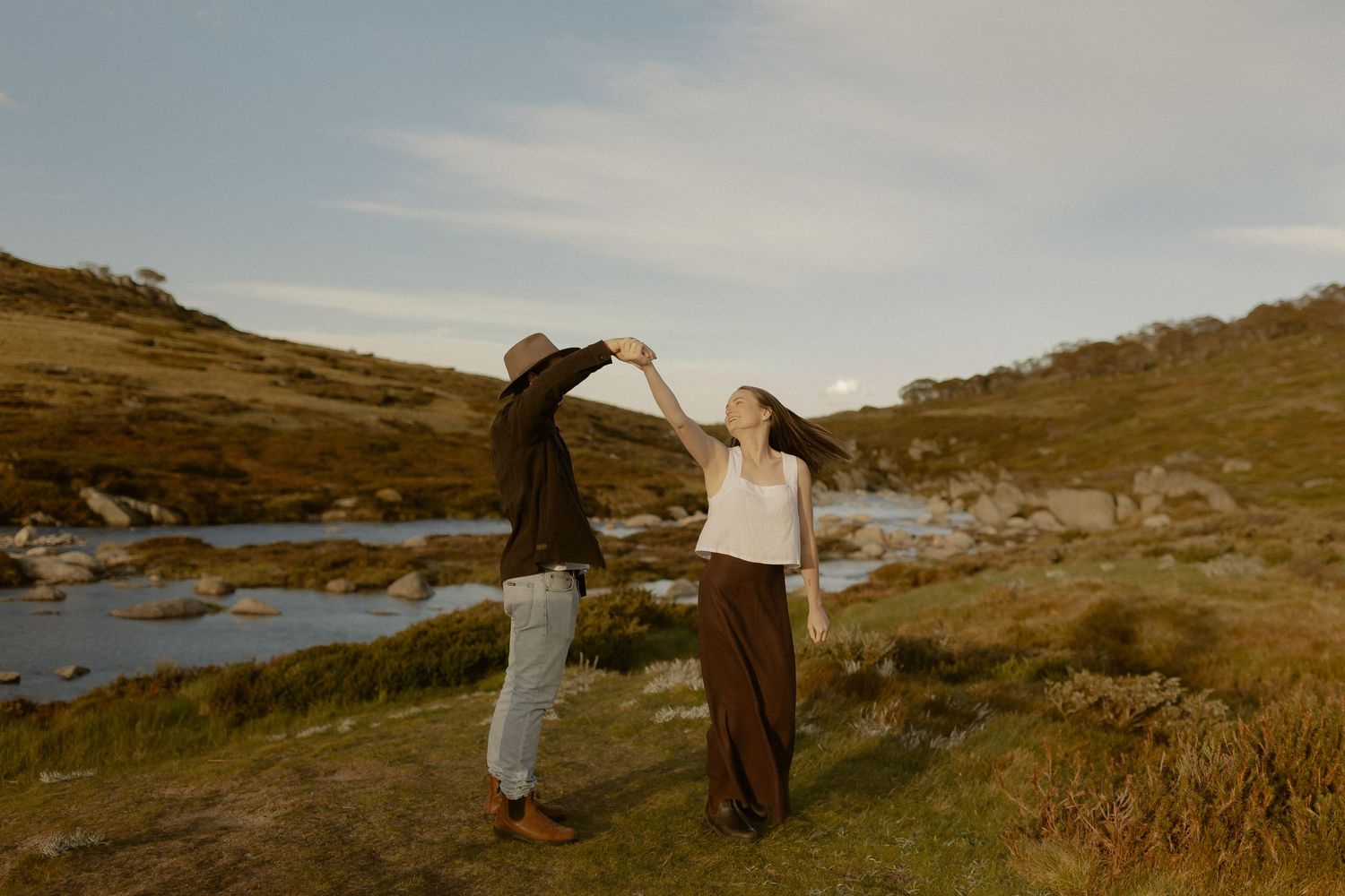 Two people share intimate moment on scenic coastal cliffs at dusk.