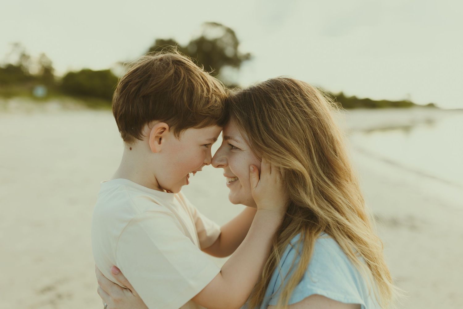 A romantic couple embraces on a sunny beach with waves crashing in the background.
