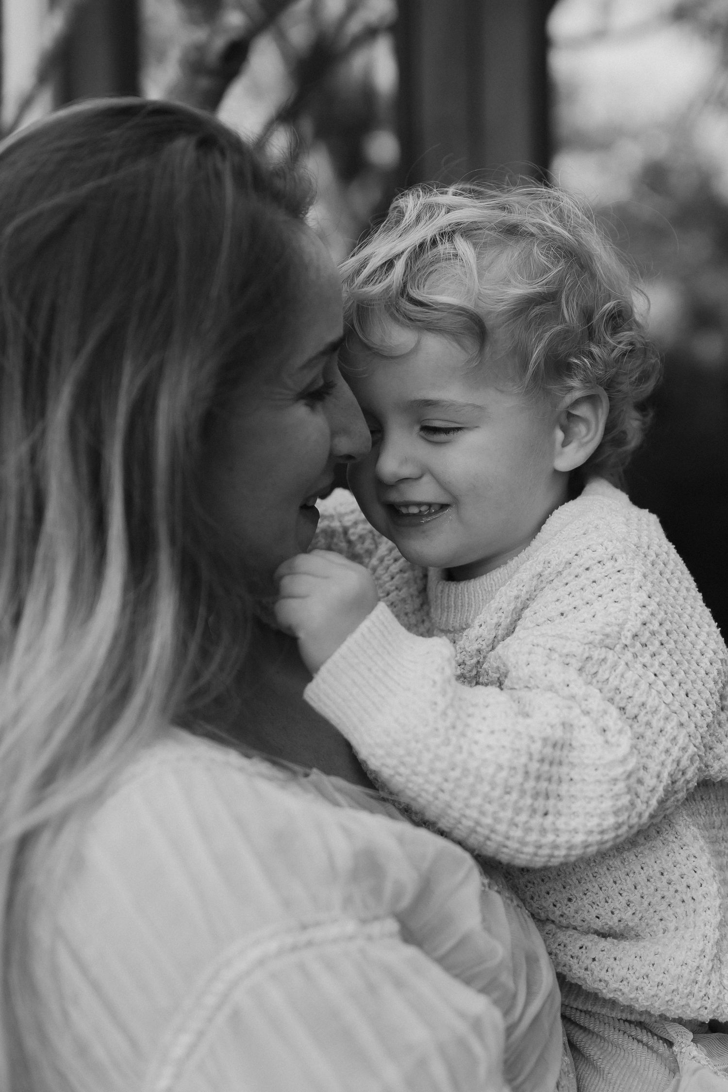 An intimate black and white portrait showing tender affection between two people in white knitwear.