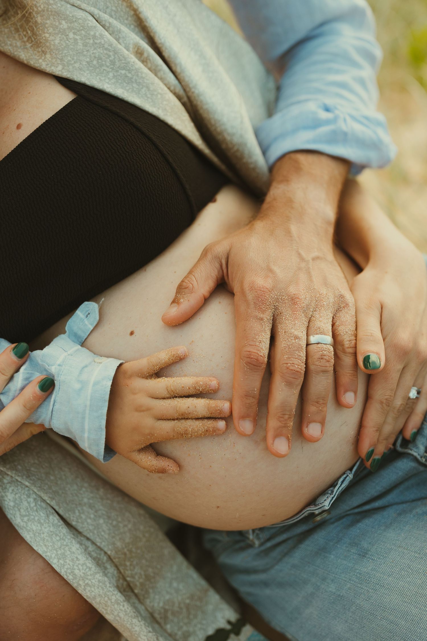 Close-up of hands with rings resting on legs showing intimate moments of affection.