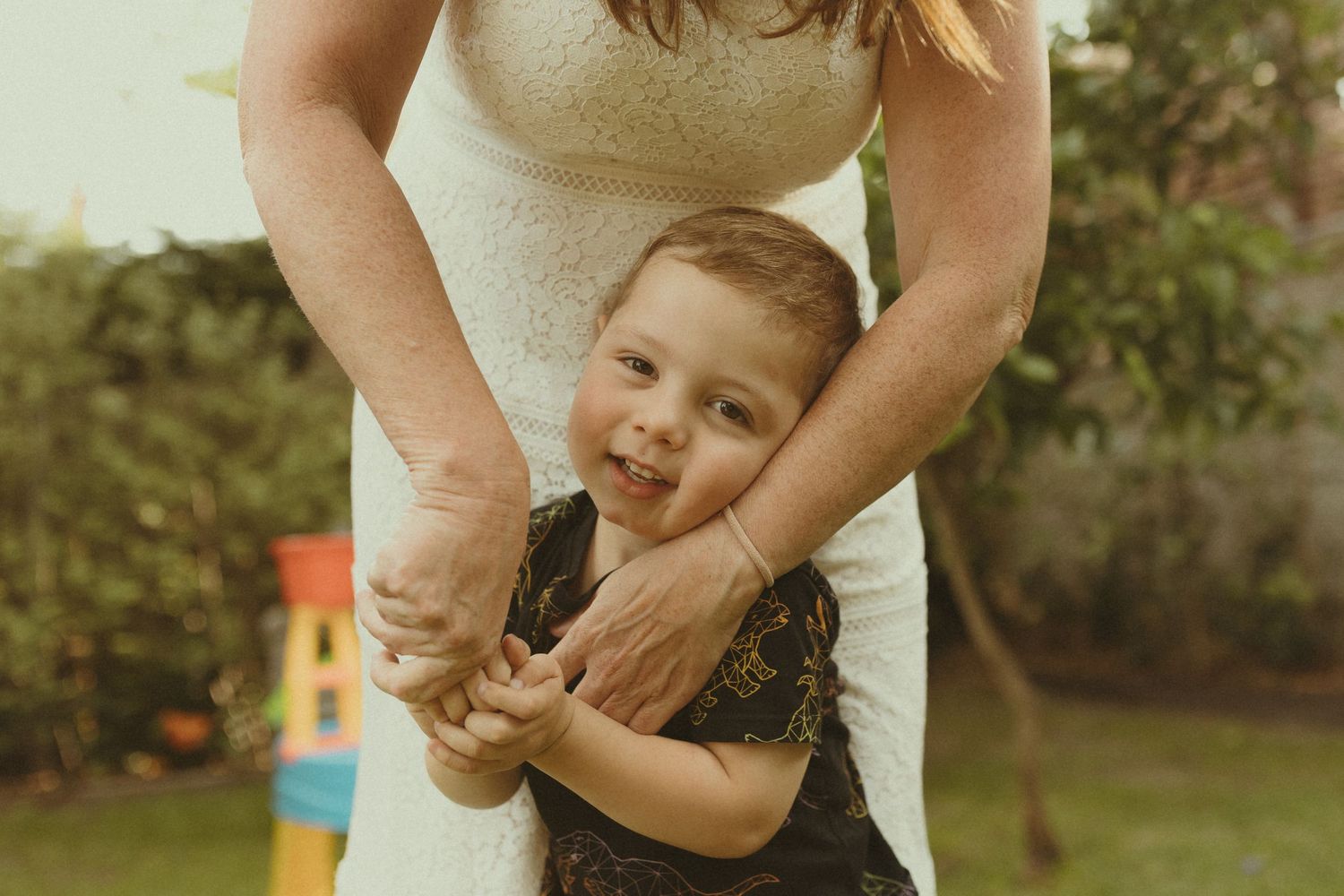 Candid family portrait showing affectionate interaction outdoors in golden afternoon light.
