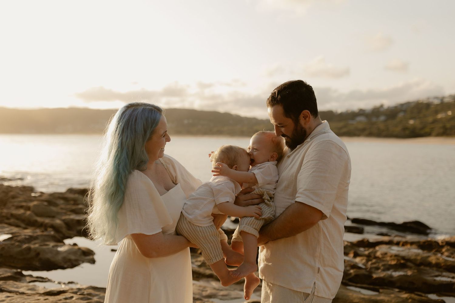 Family enjoying intimate moments together on scenic coastal beach at sunset.