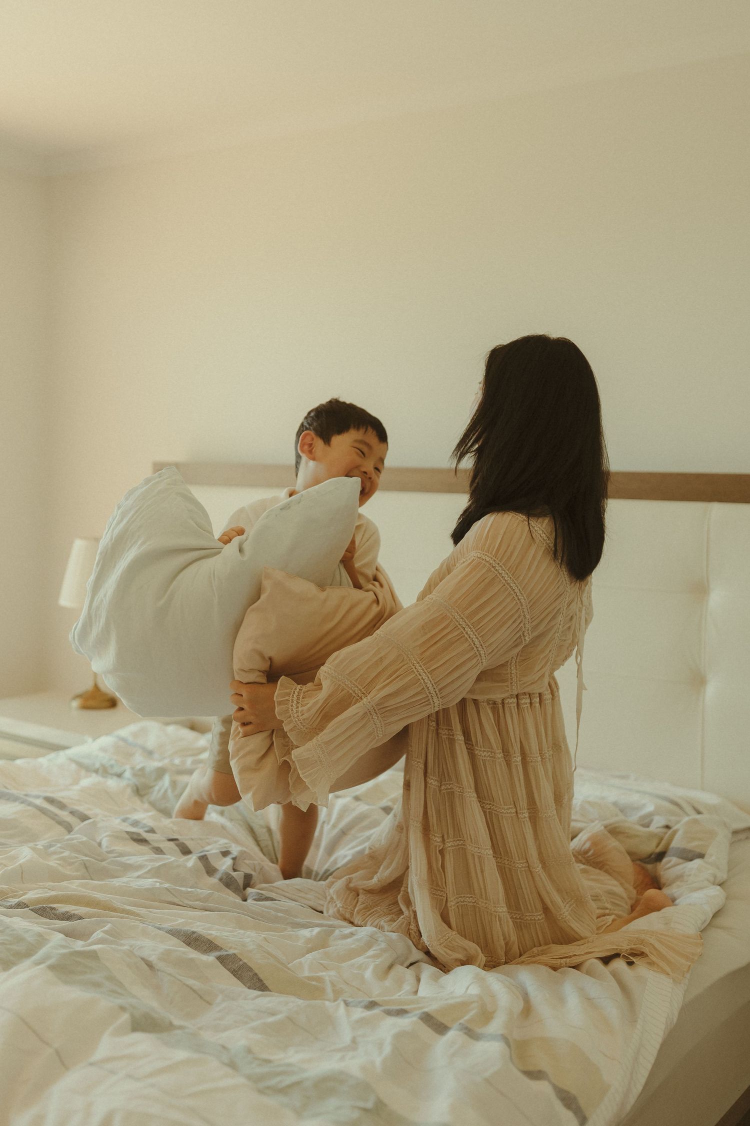 People sharing playful moments together on a white bed with rumpled sheets.