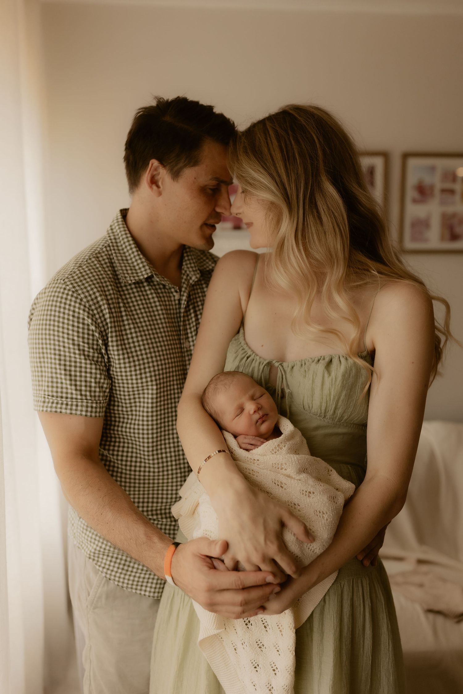 A tender family moment captured in a series of intimate lifestyle photographs showing parents bonding with their newborn baby.