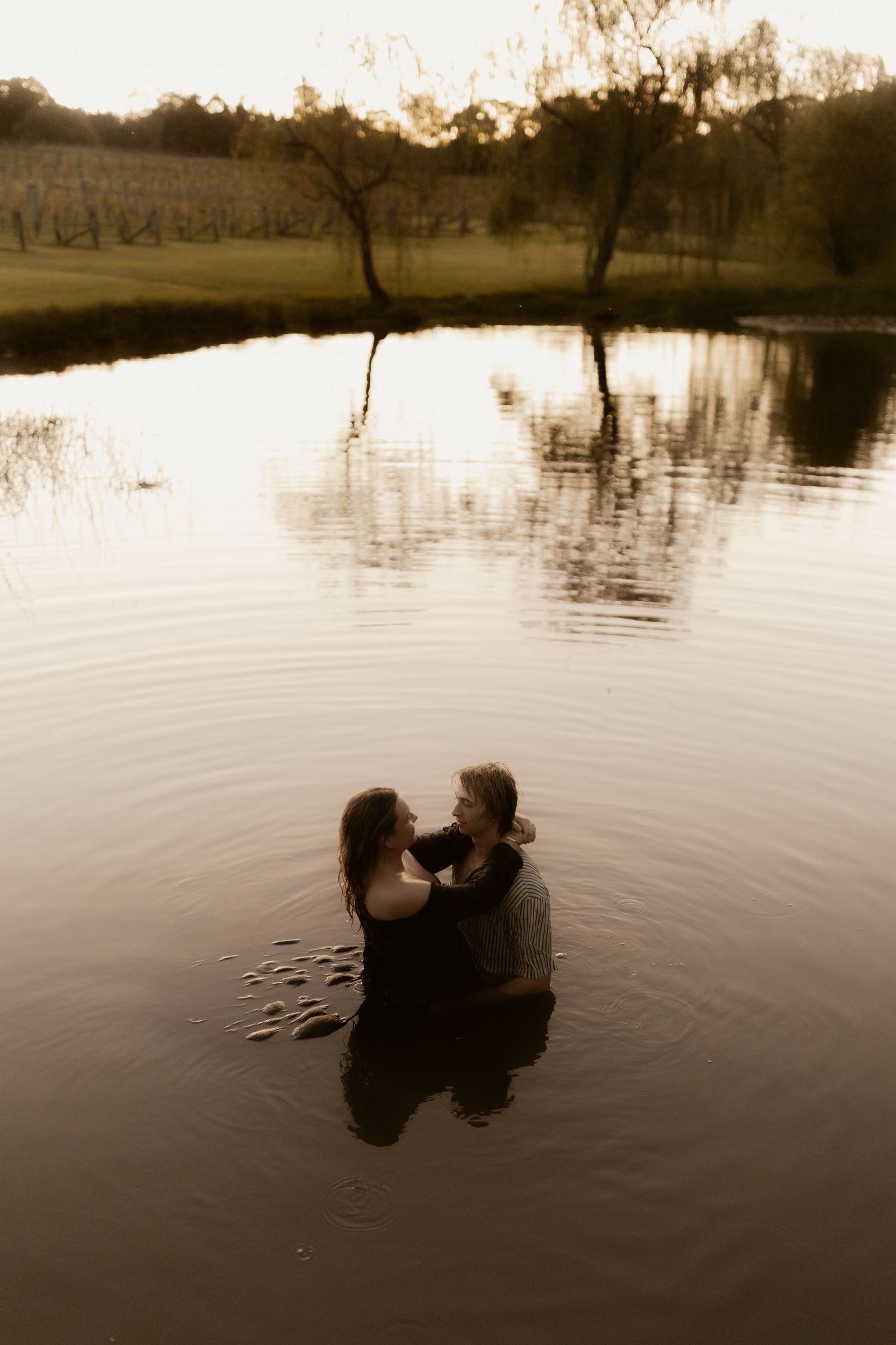Romantic silhouettes reflected in calm lake water at sunset creating a dreamy atmosphere.