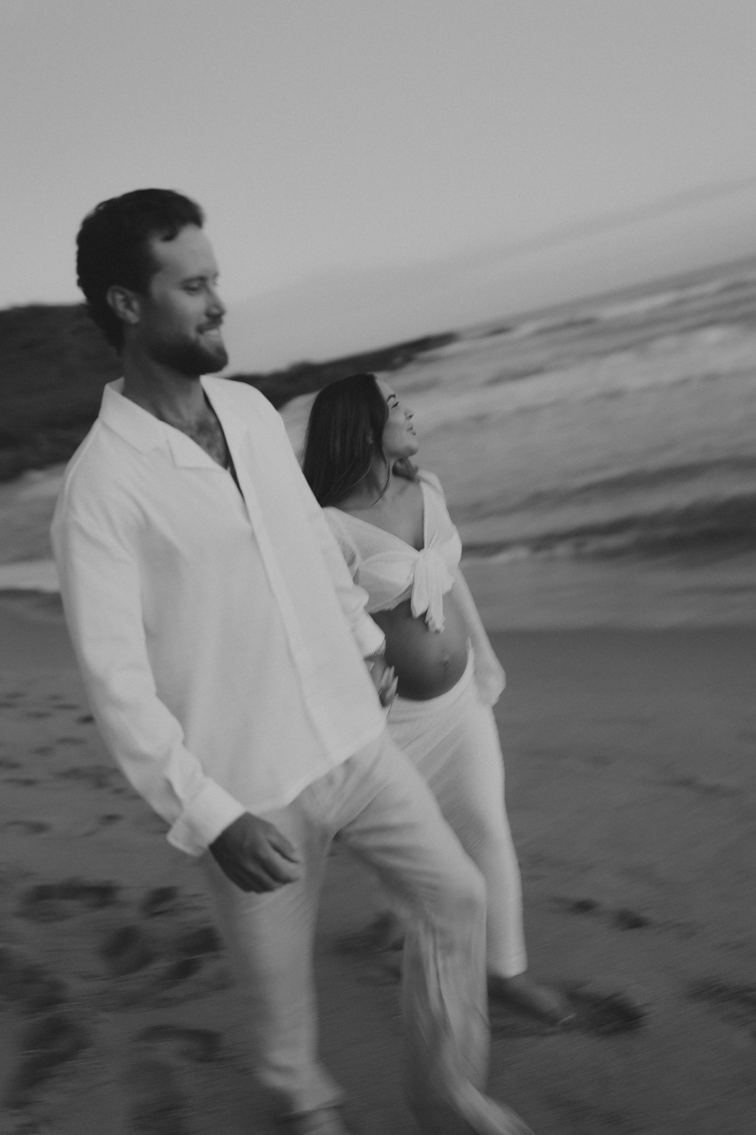 Black and white photos of couple dancing and moving together on beach with motion blur effects.