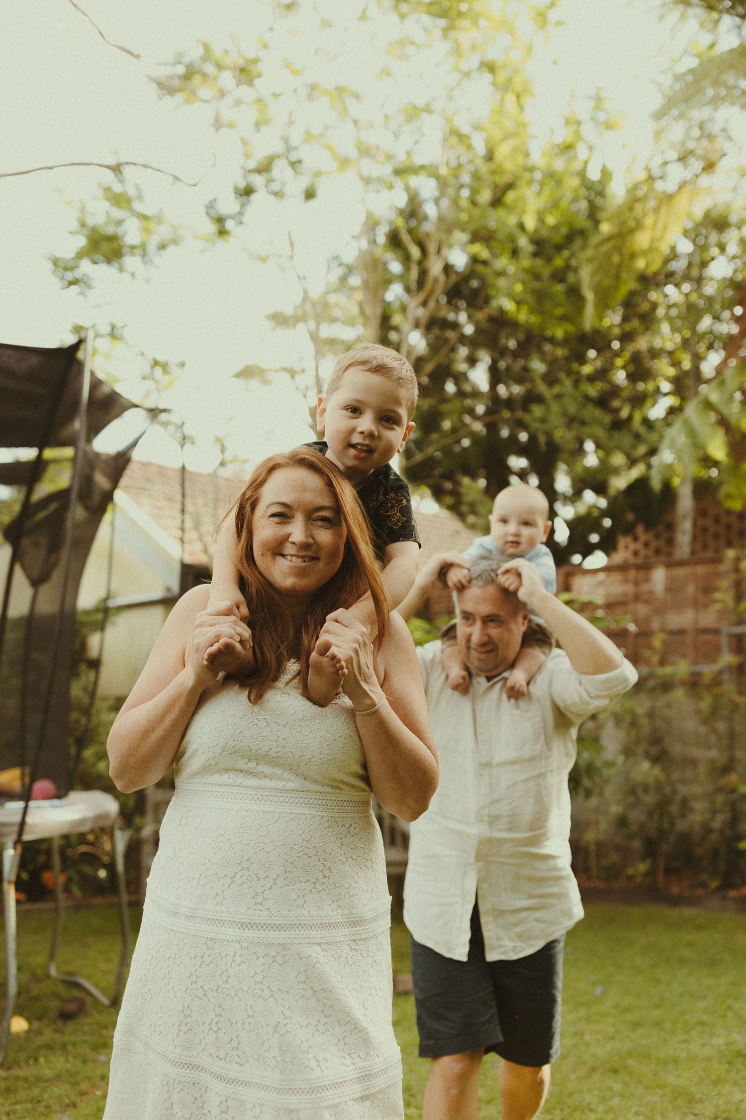 Playful outdoor family photos showing joyful expressions and interactions in a backyard setting.