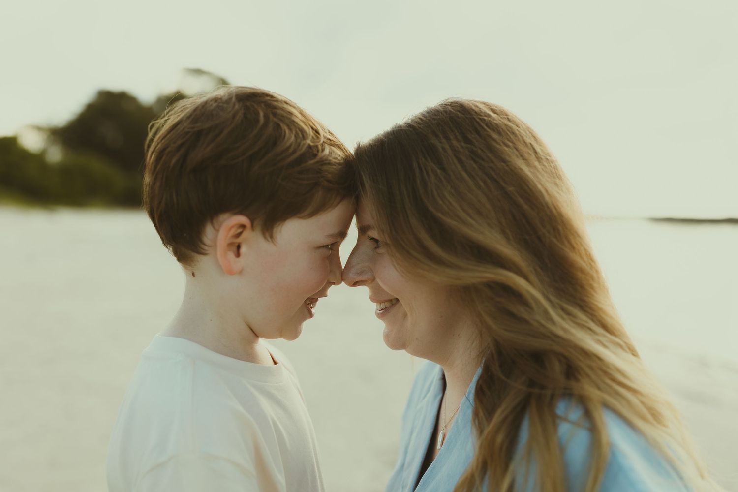 An intimate family moment captured in warm sunlight on the beach.