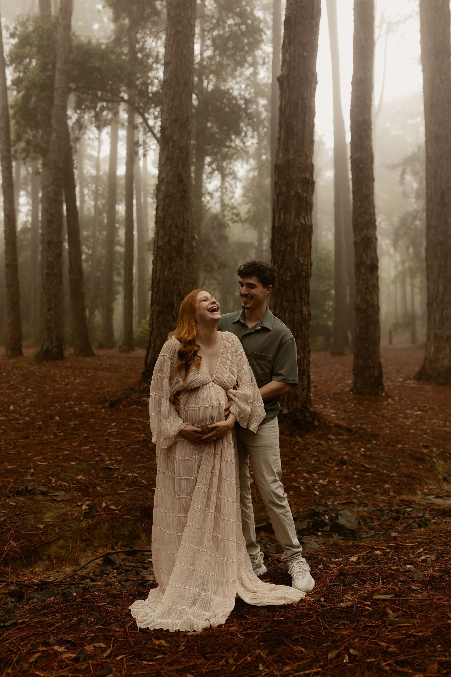 Romantic couple shares intimate moments in a misty forest with autumn leaves scattered on the ground.