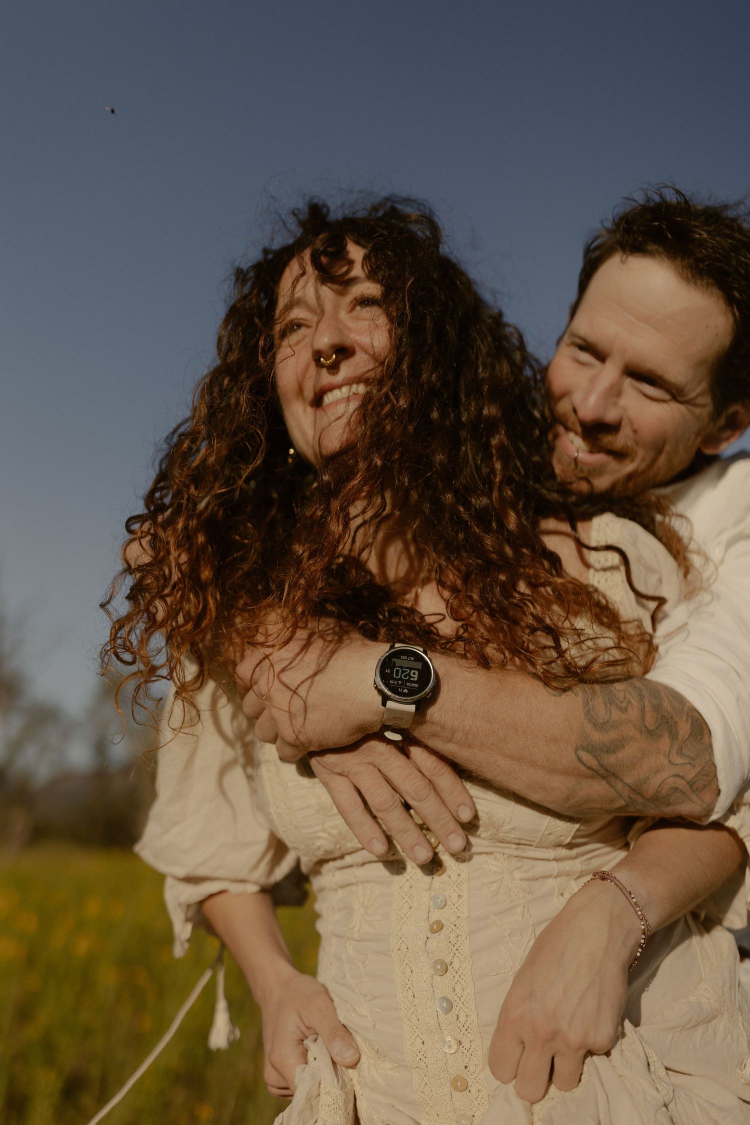 A romantic embrace captured in a golden field during sunset with light streaming through.