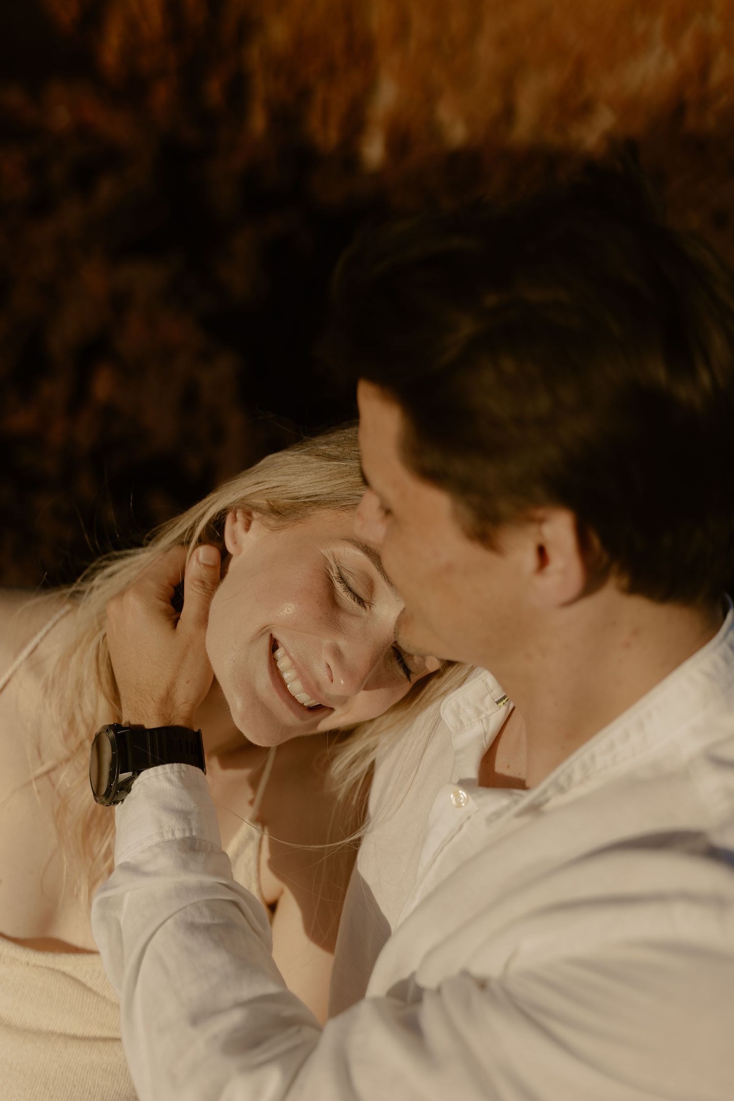 A romantic couple sharing intimate moments while lying down together in soft lighting.
