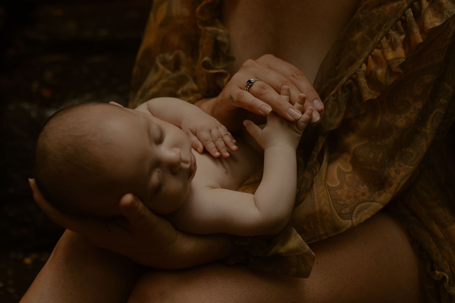 Two hands gently embrace in a tender moment against a dark background.