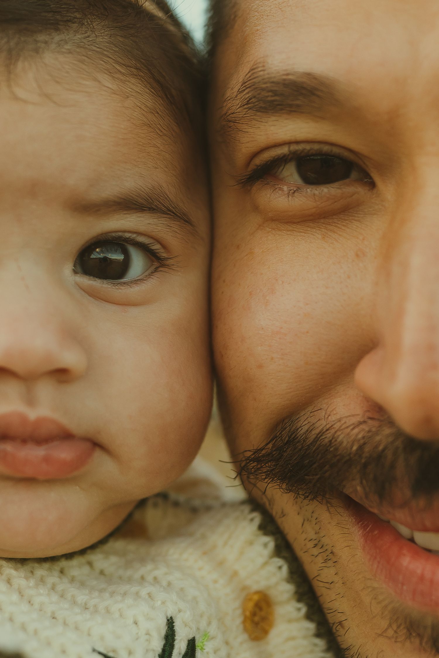 Close-up portrait showing a warm tender moment between parent and child with gentle smiles.