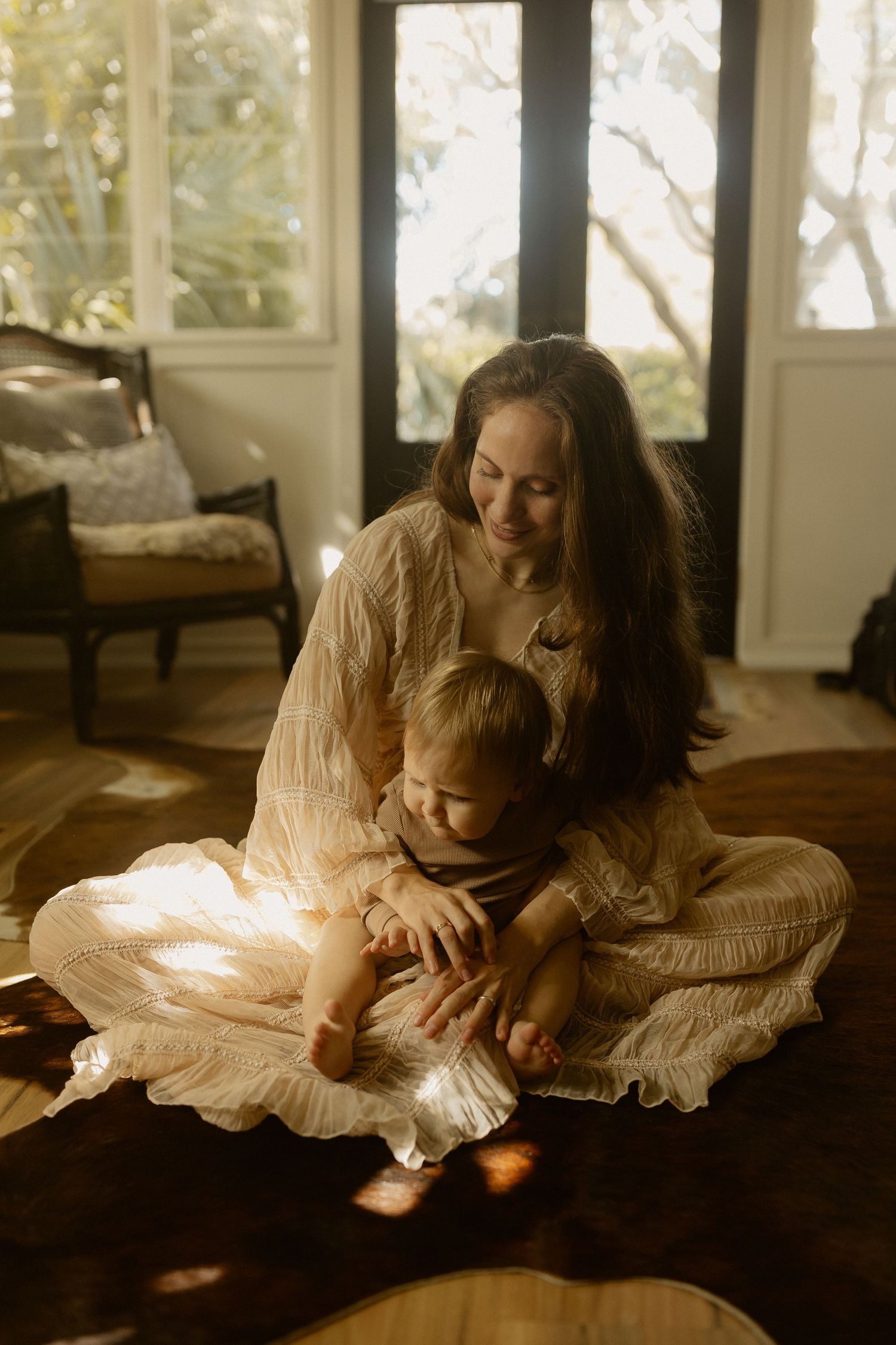 Intimate family photography with soft golden lighting and natural window glow.