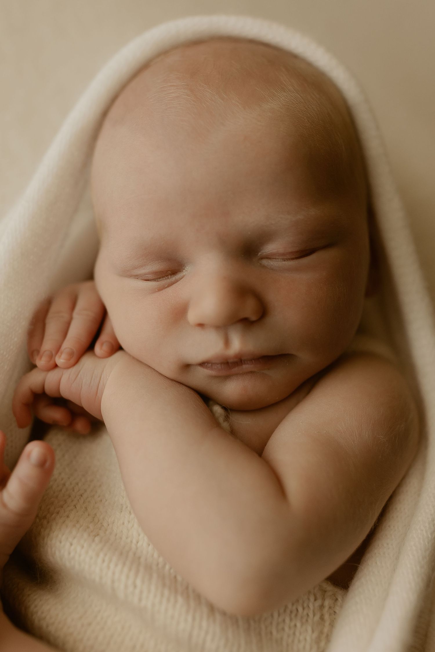 A peaceful sleeping newborn baby wrapped in soft white fabric is captured in multiple gentle close-up views.