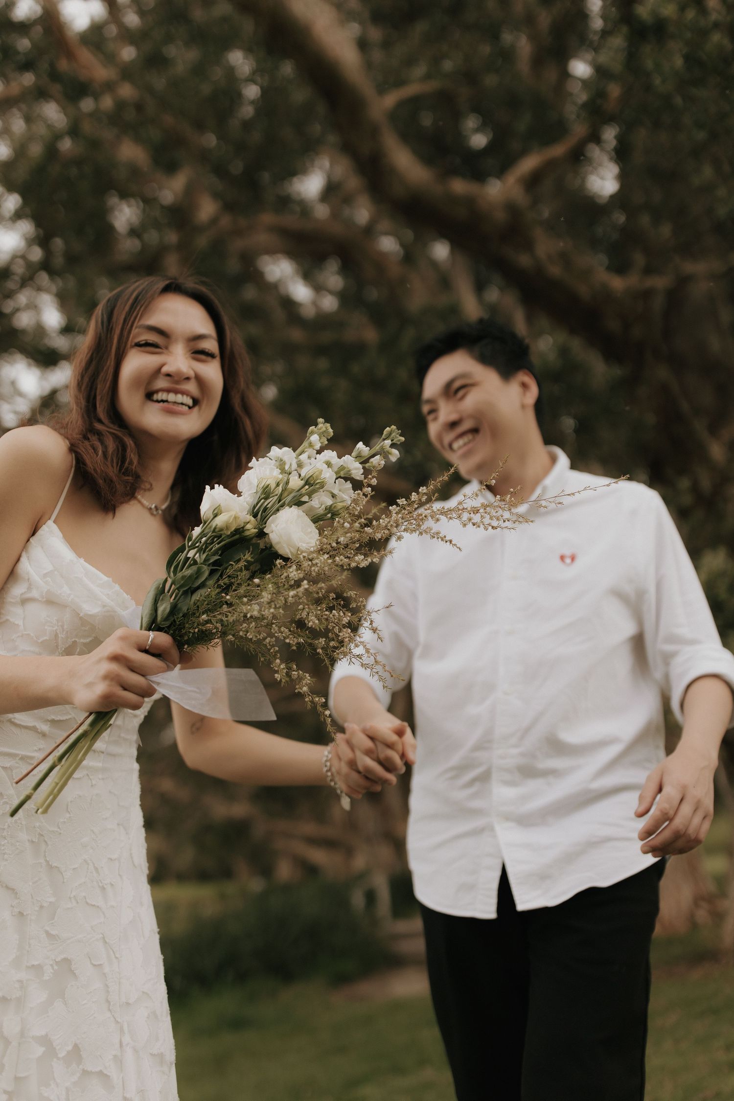 A romantic couple in white outfits share joyful moments together in a natural outdoor setting.