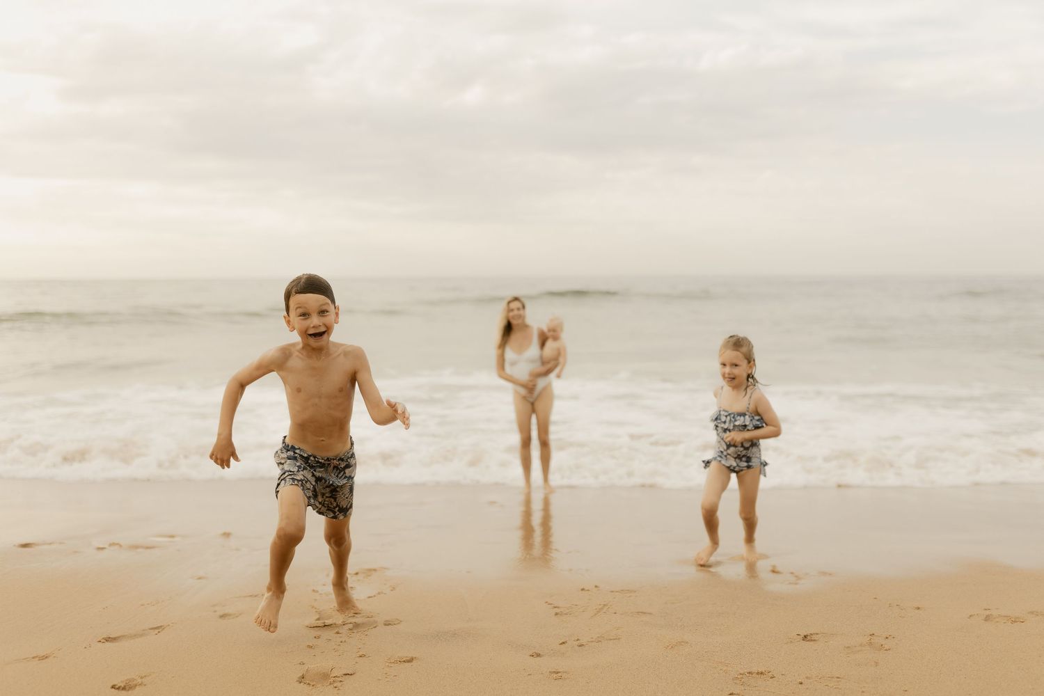 Family enjoying a day at the beach with children playing in the sand and waves.