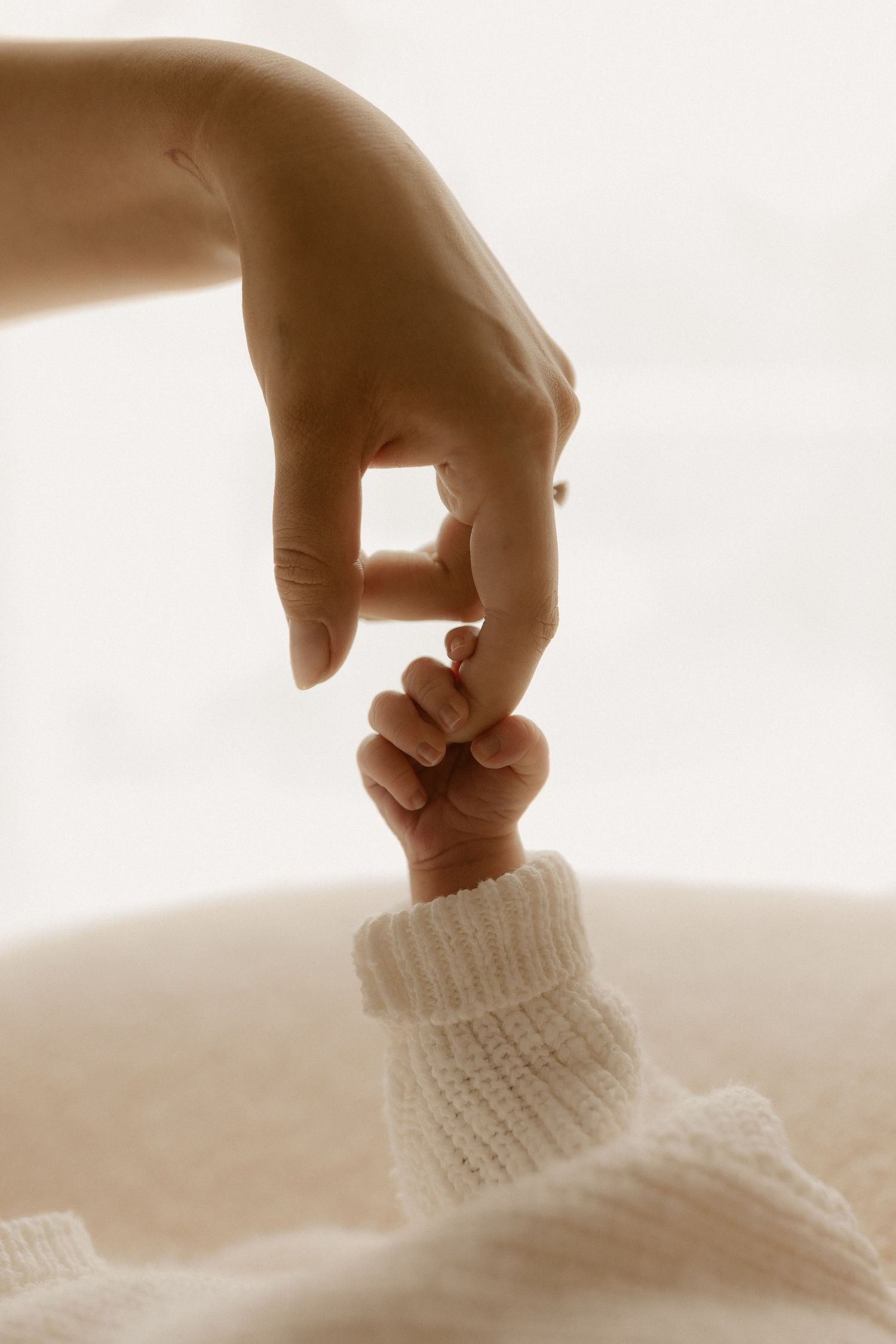 Close-up sequence of a hand gently touching a soft white knitted fabric surface in warm lighting.