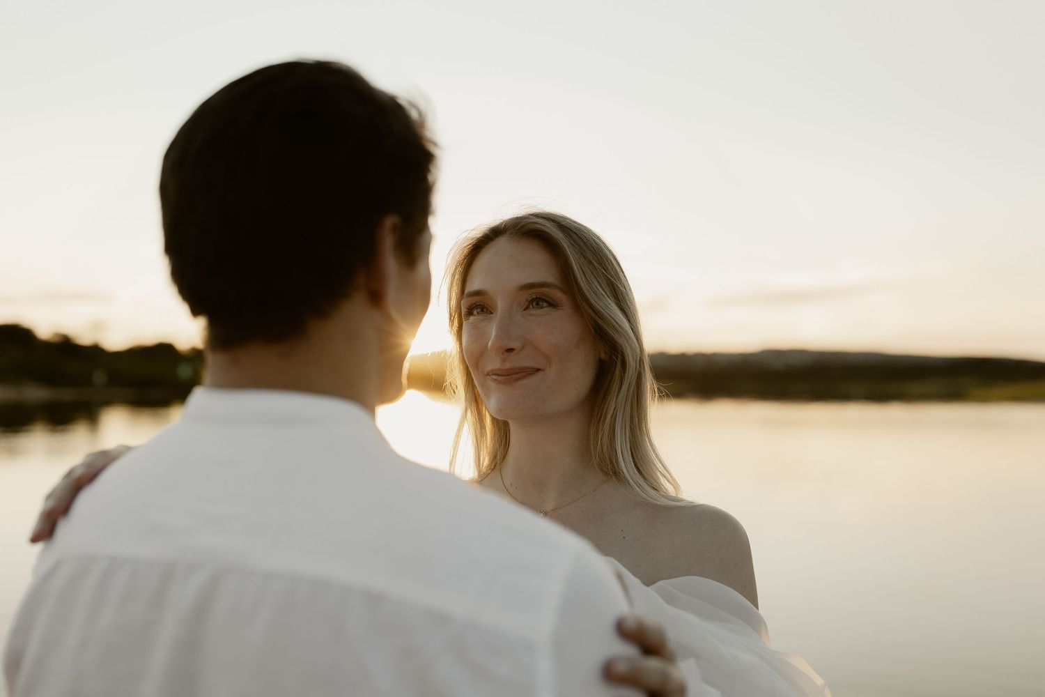 Intimate couple portrait silhouetted against a serene lakeside sunset.